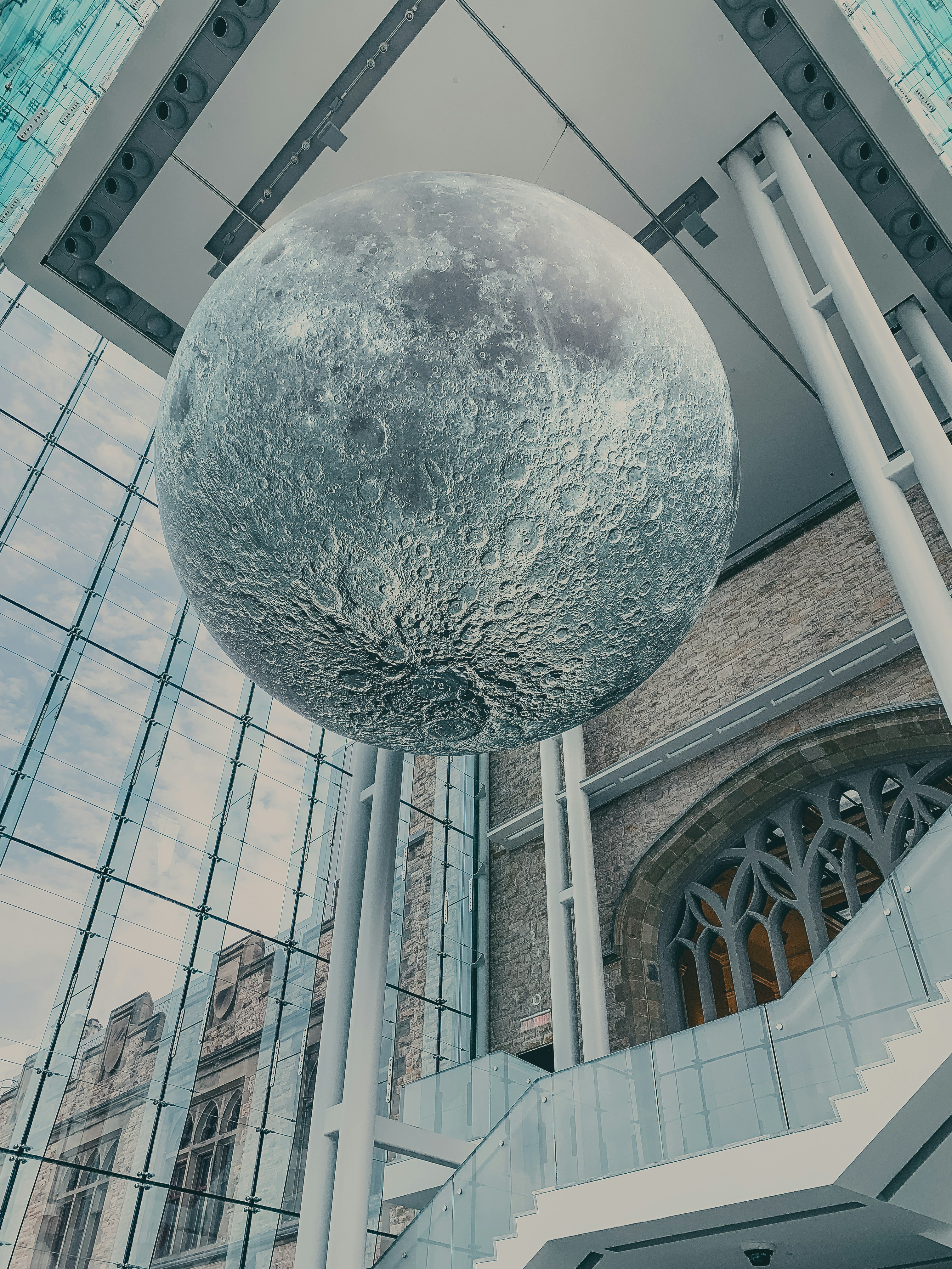 A large metal ball hanging from the side of a building