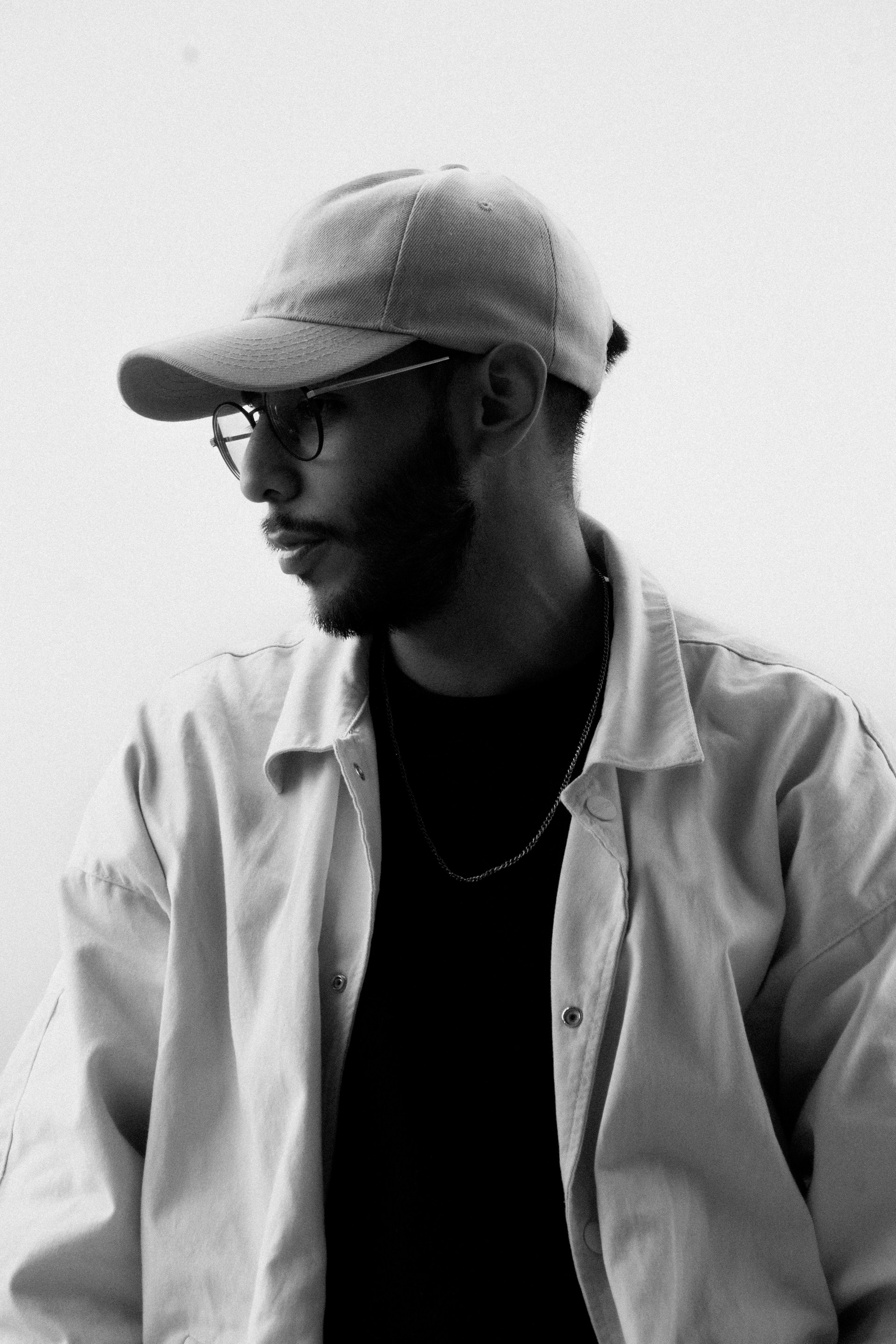 A man wearing a hat and glasses sitting down