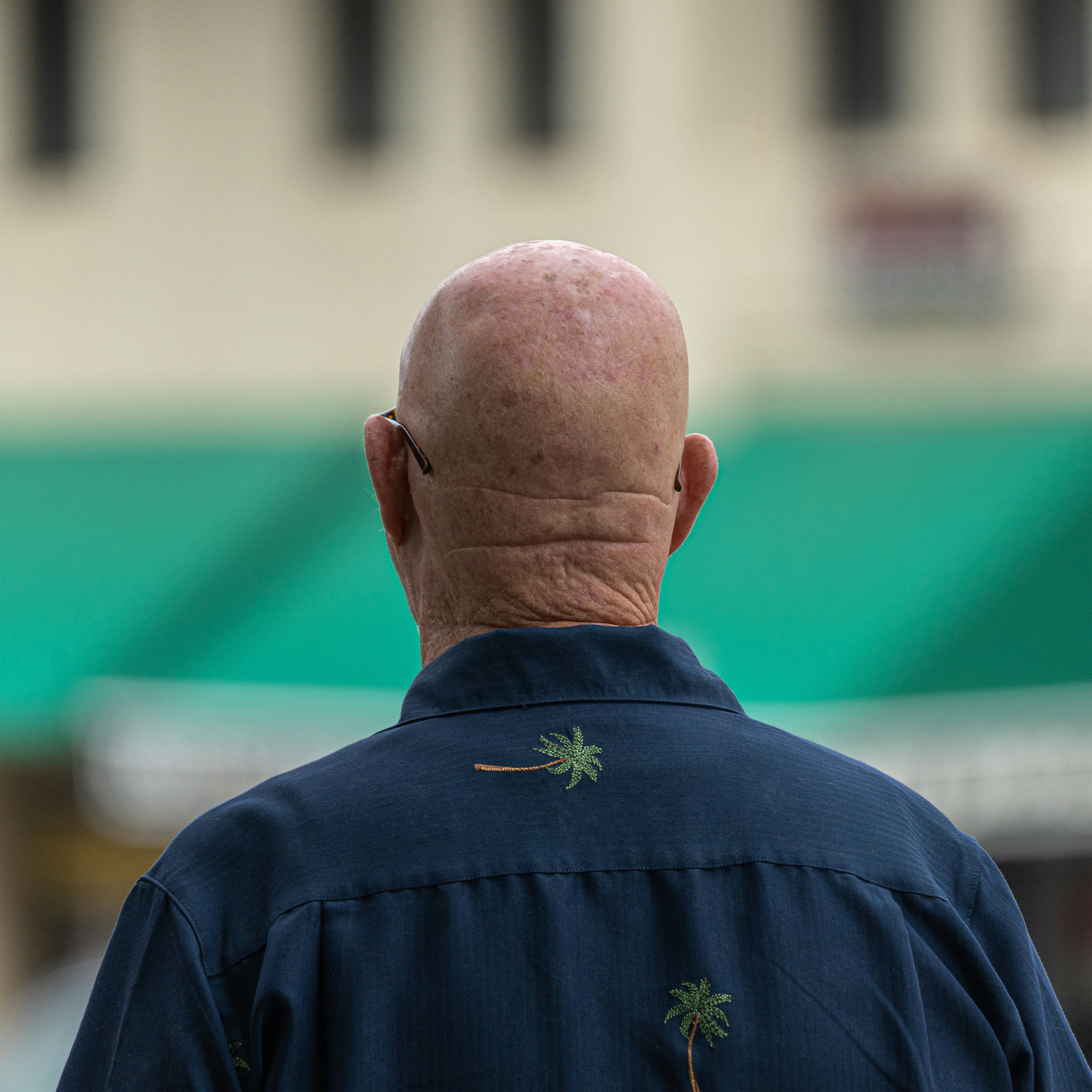 A man with a bald head walking down a street