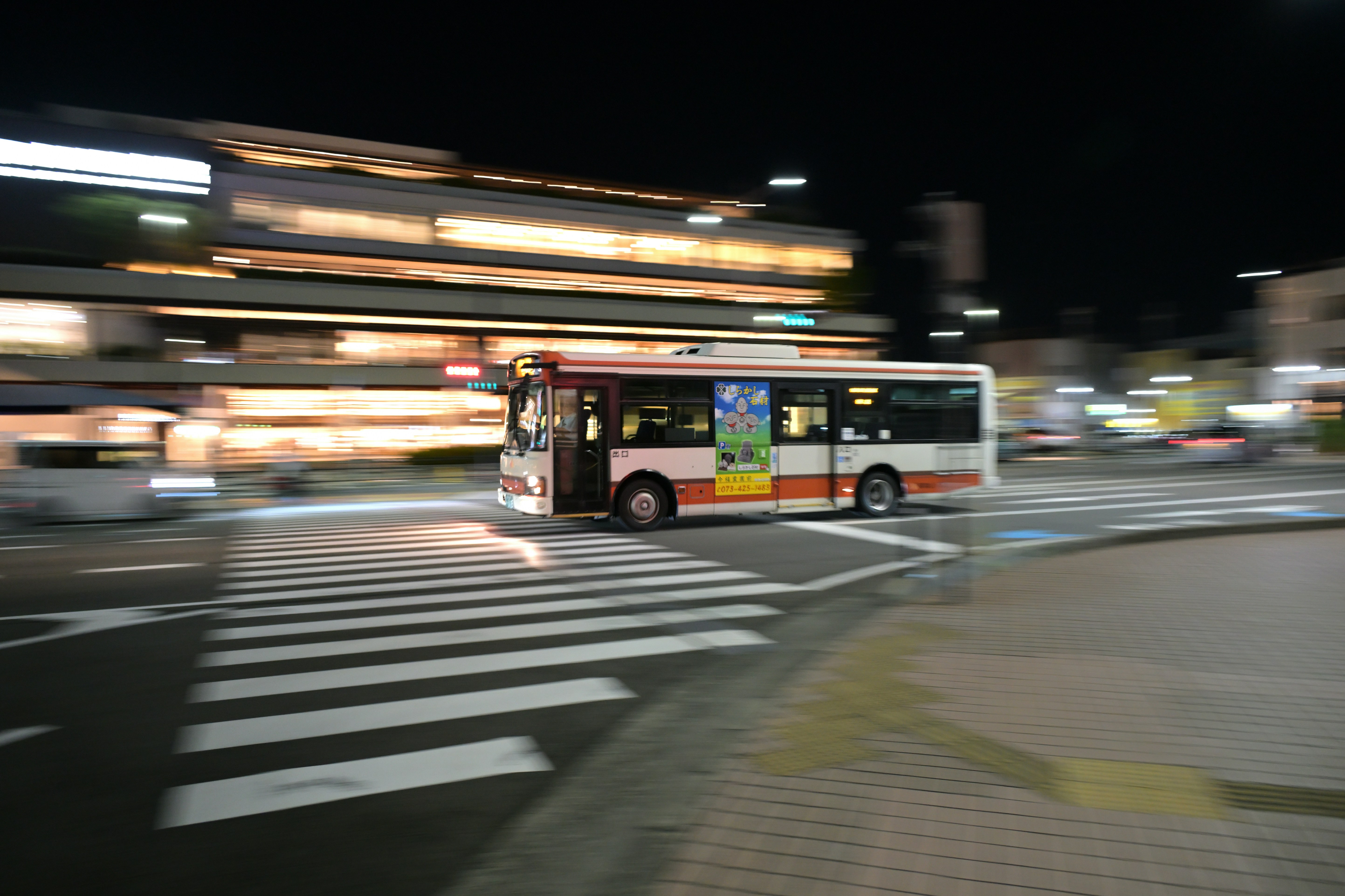 A city bus driving down a street at night