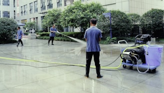 A man is using a power washer to clean the street