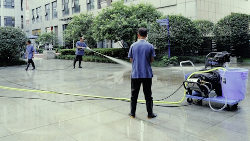 A man is using a power washer to clean the street