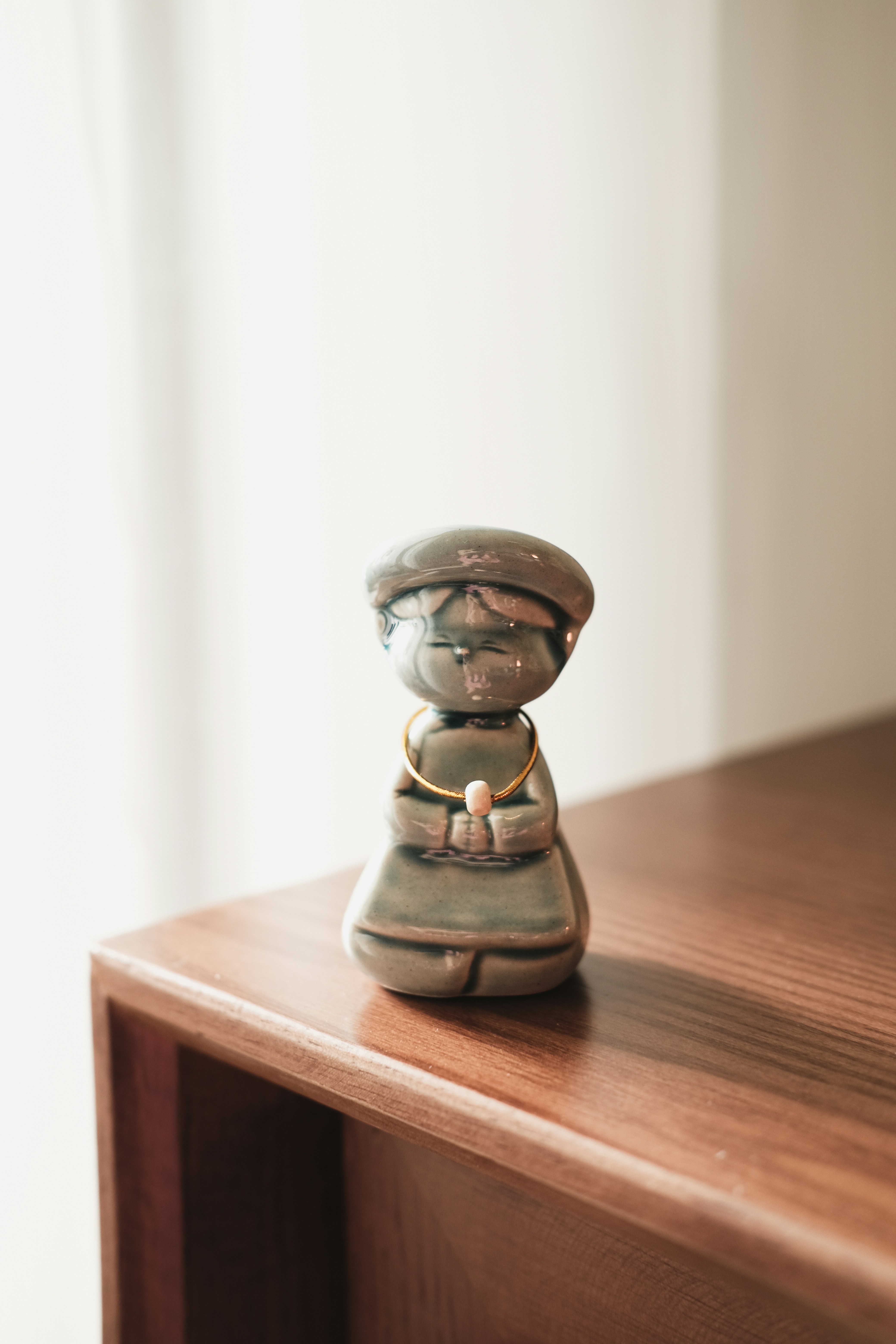 A small figurine sitting on top of a wooden shelf