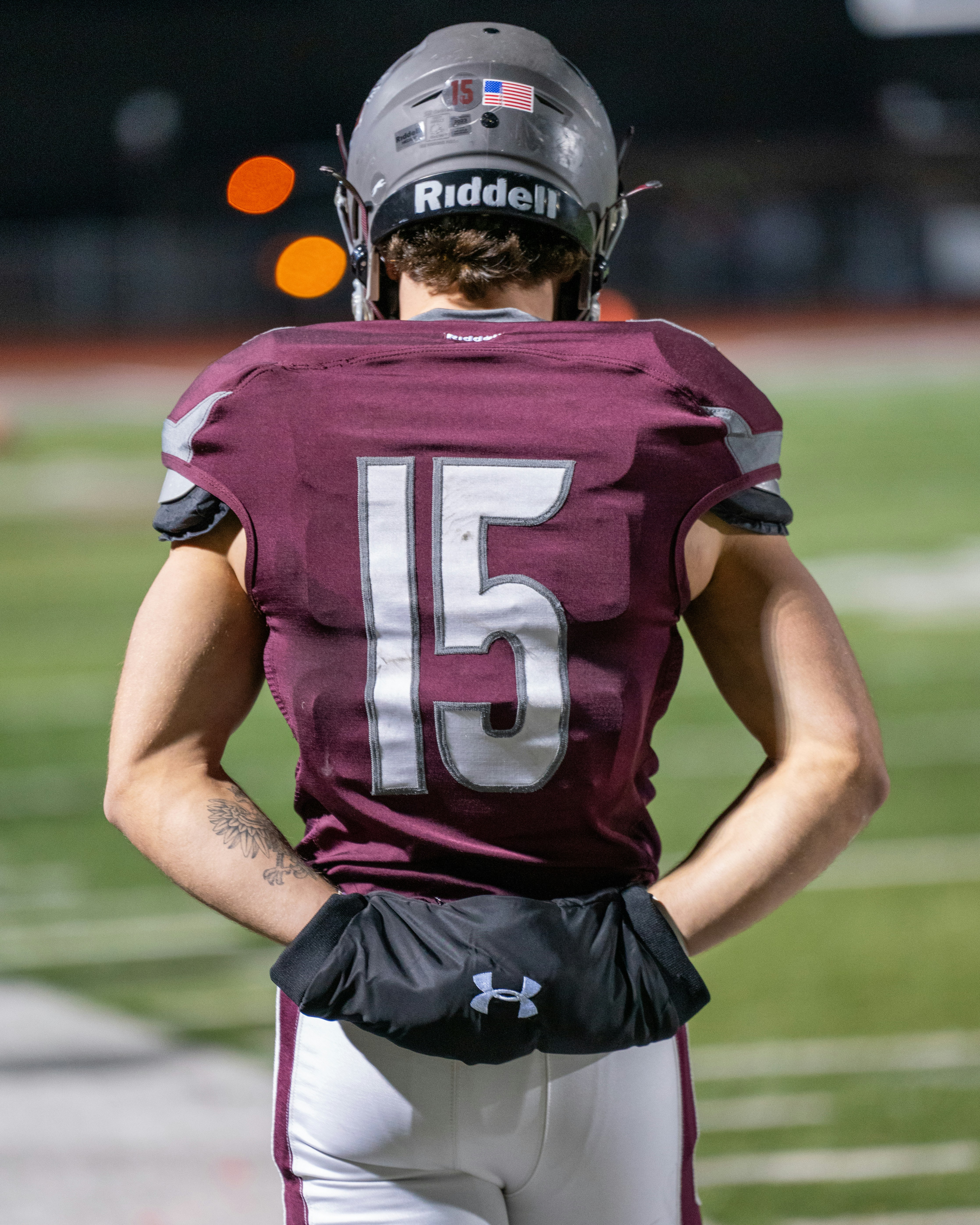 A football player standing on a field with his hands on his hips