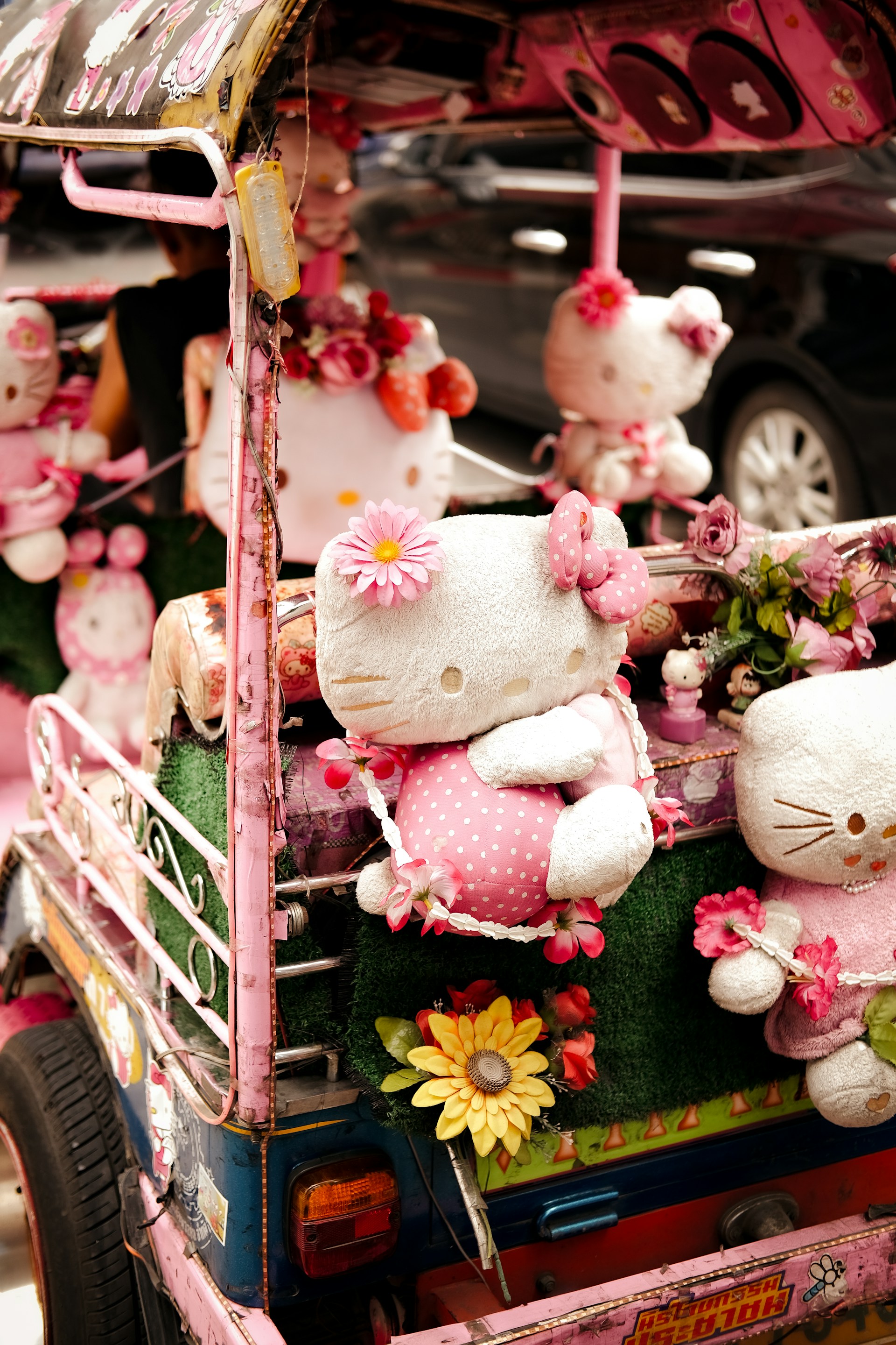 A pink car with hello kitty stuffed animals in the back