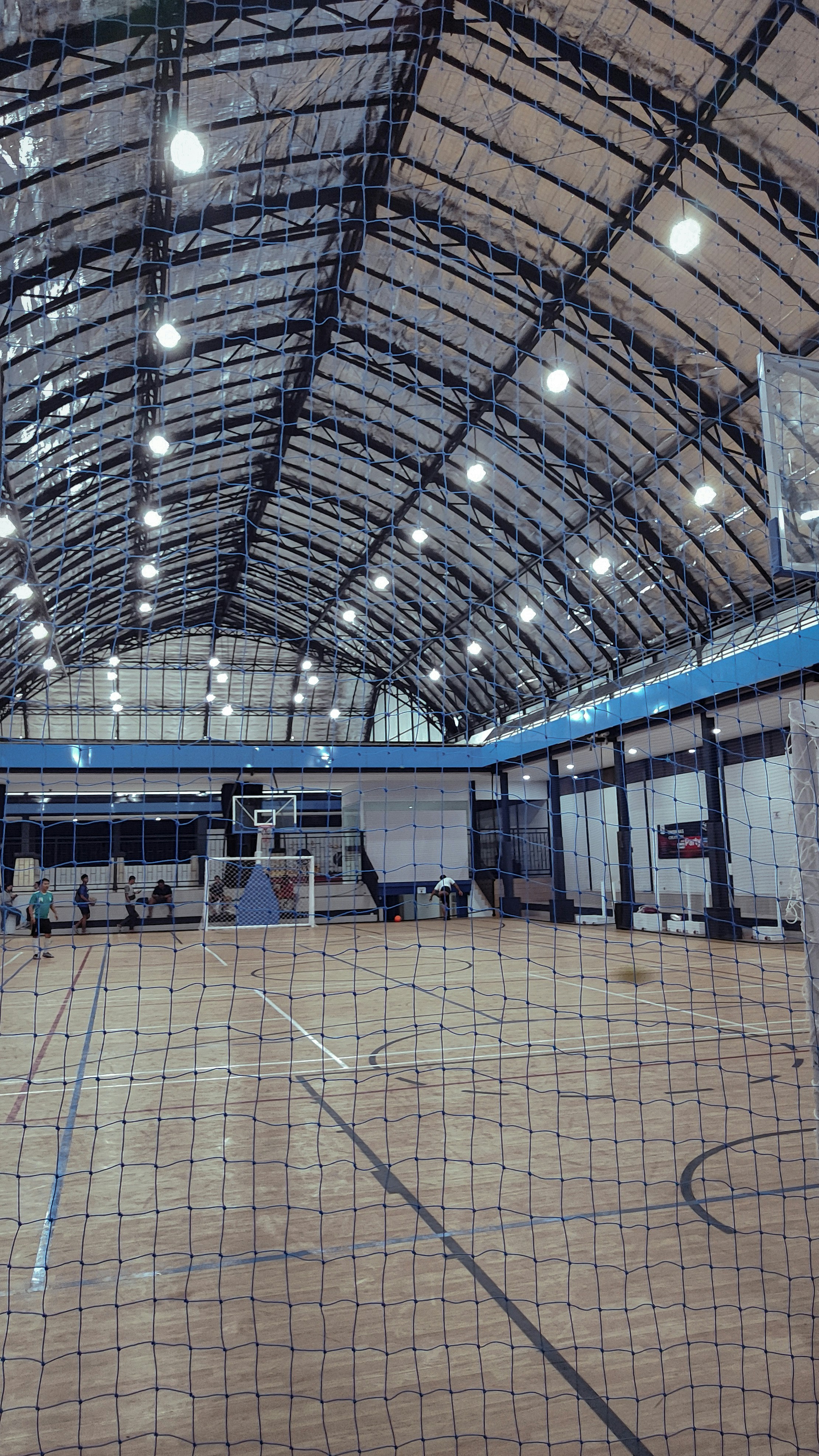 Players warming up on indoor sports court, active athletic movement, bright indoor lighting