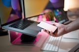 A person holding a cell phone next to a laptop