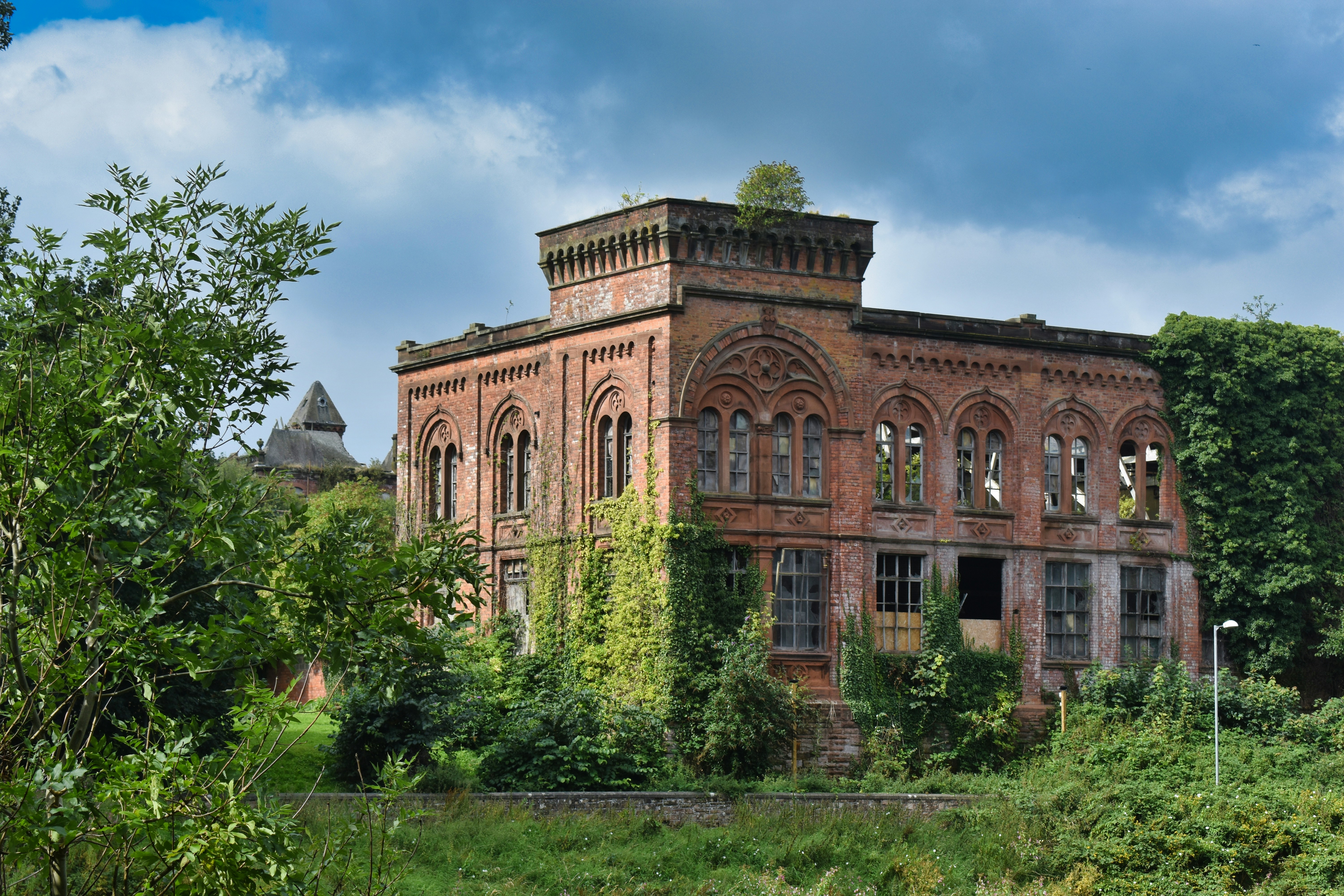 An old brick building sitting in the middle of a lush green field