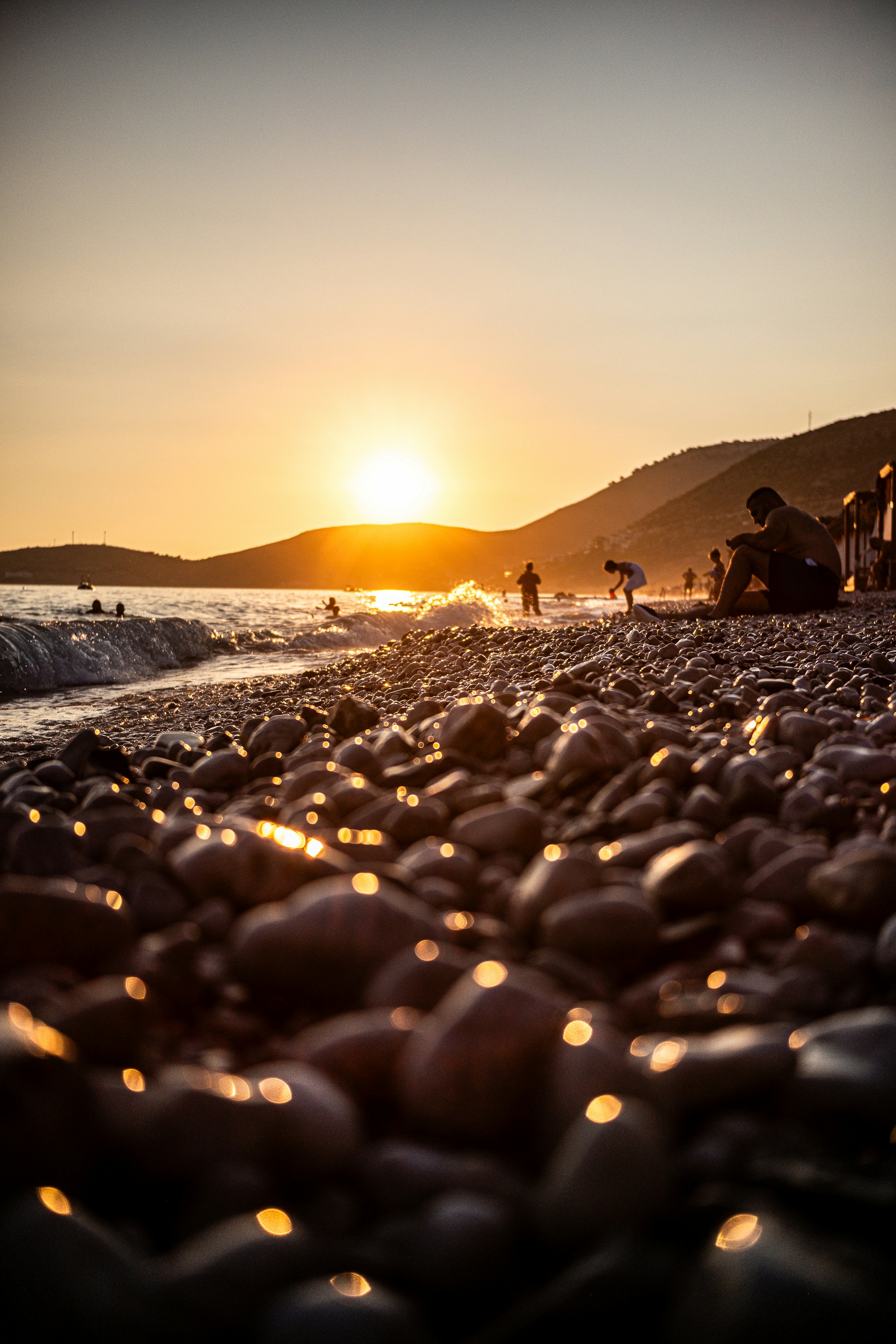 The sun is setting over a rocky beach