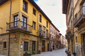 A narrow street lined with yellow buildings and balconies
