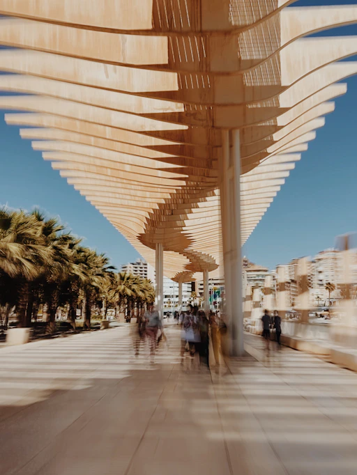 A group of people walking down a sidewalk next to palm trees