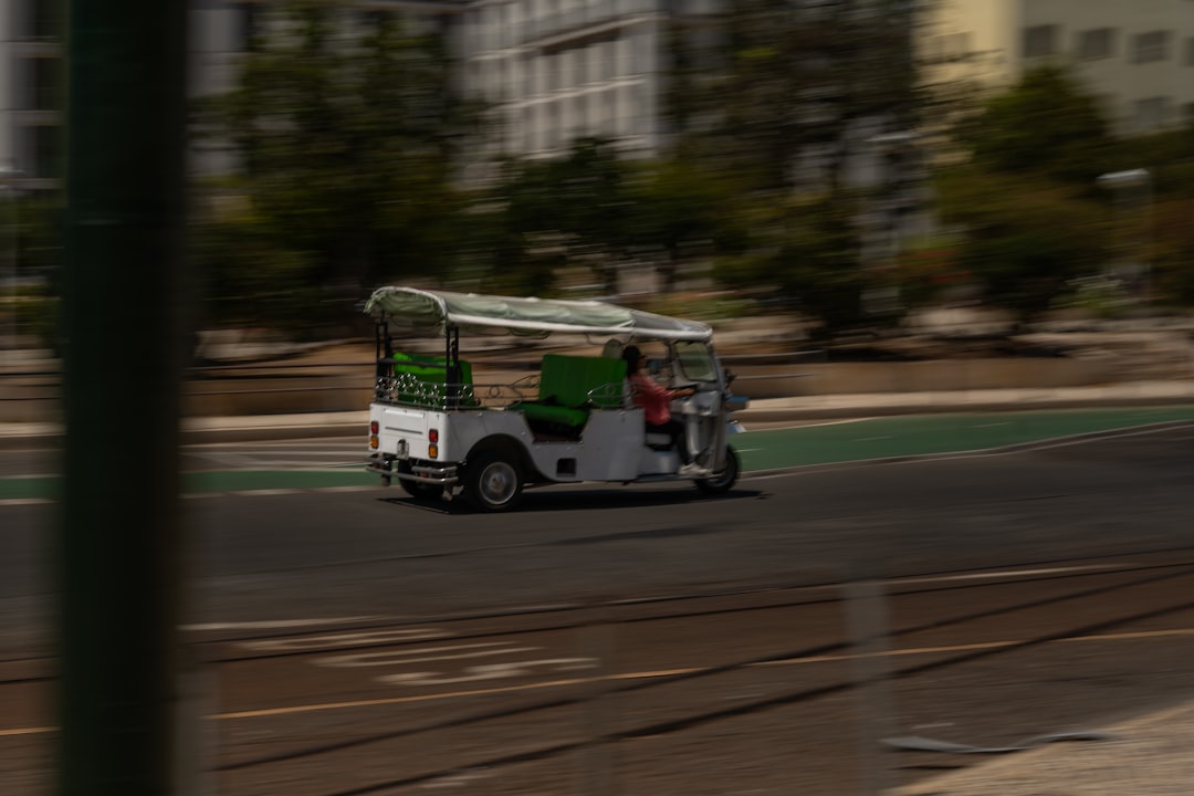 A golf cart driving down a street next to tall buildings, TukTuk