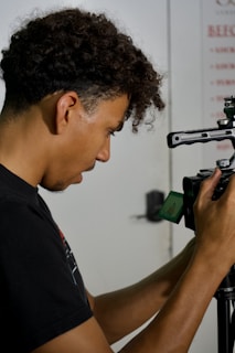 A man holding a camera up to a tripod
