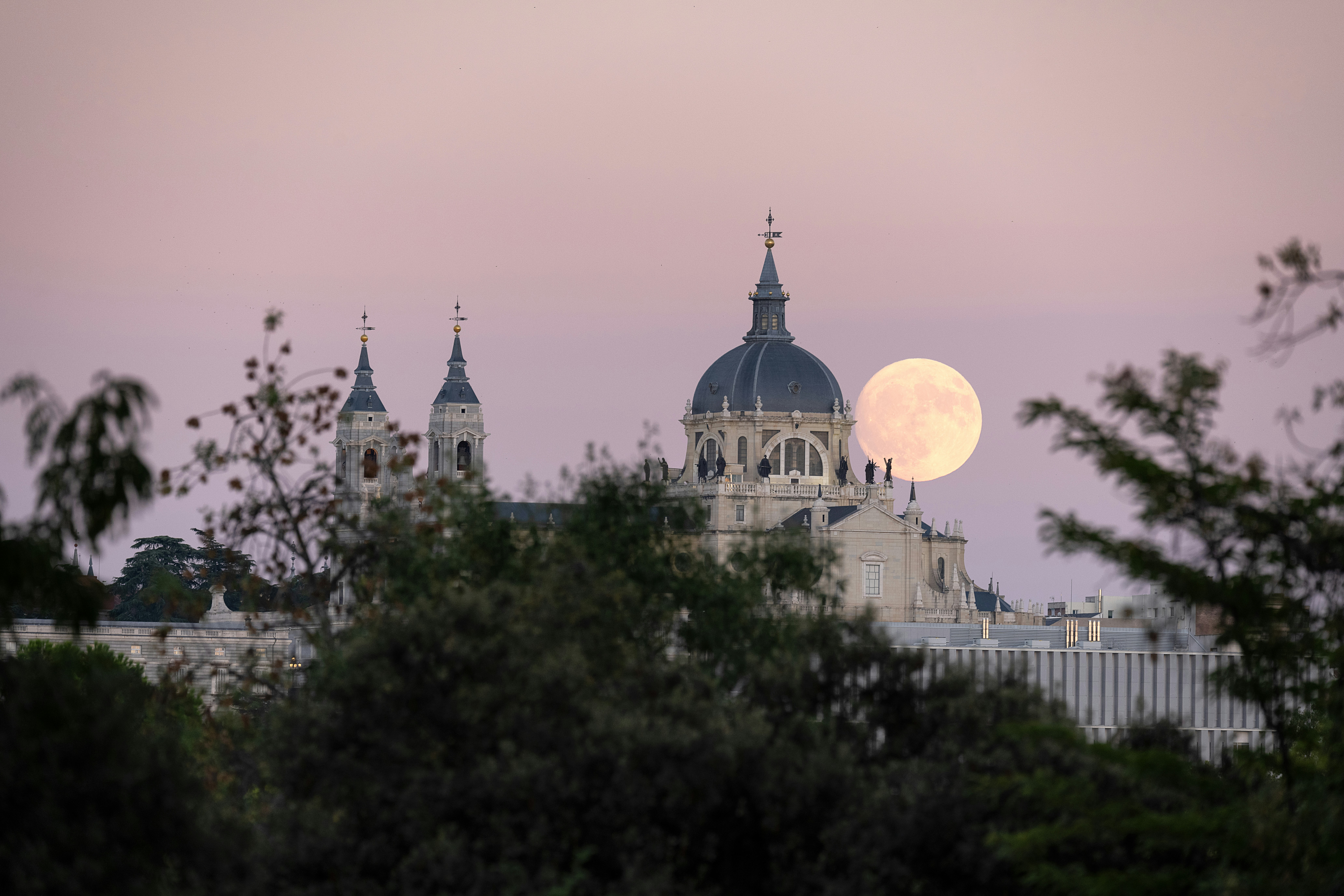A full moon rises over a city skyline