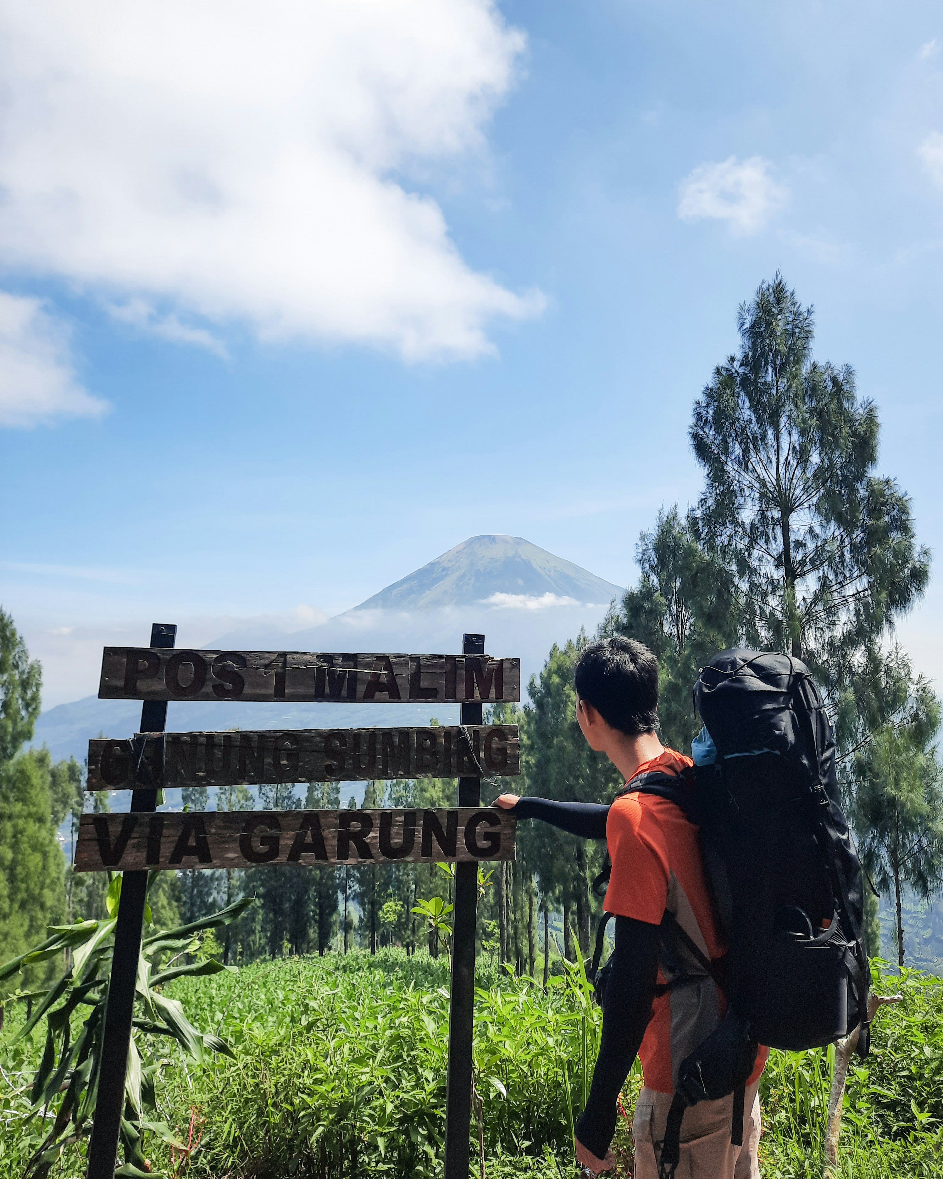 A man with a backpack standing next to a sign