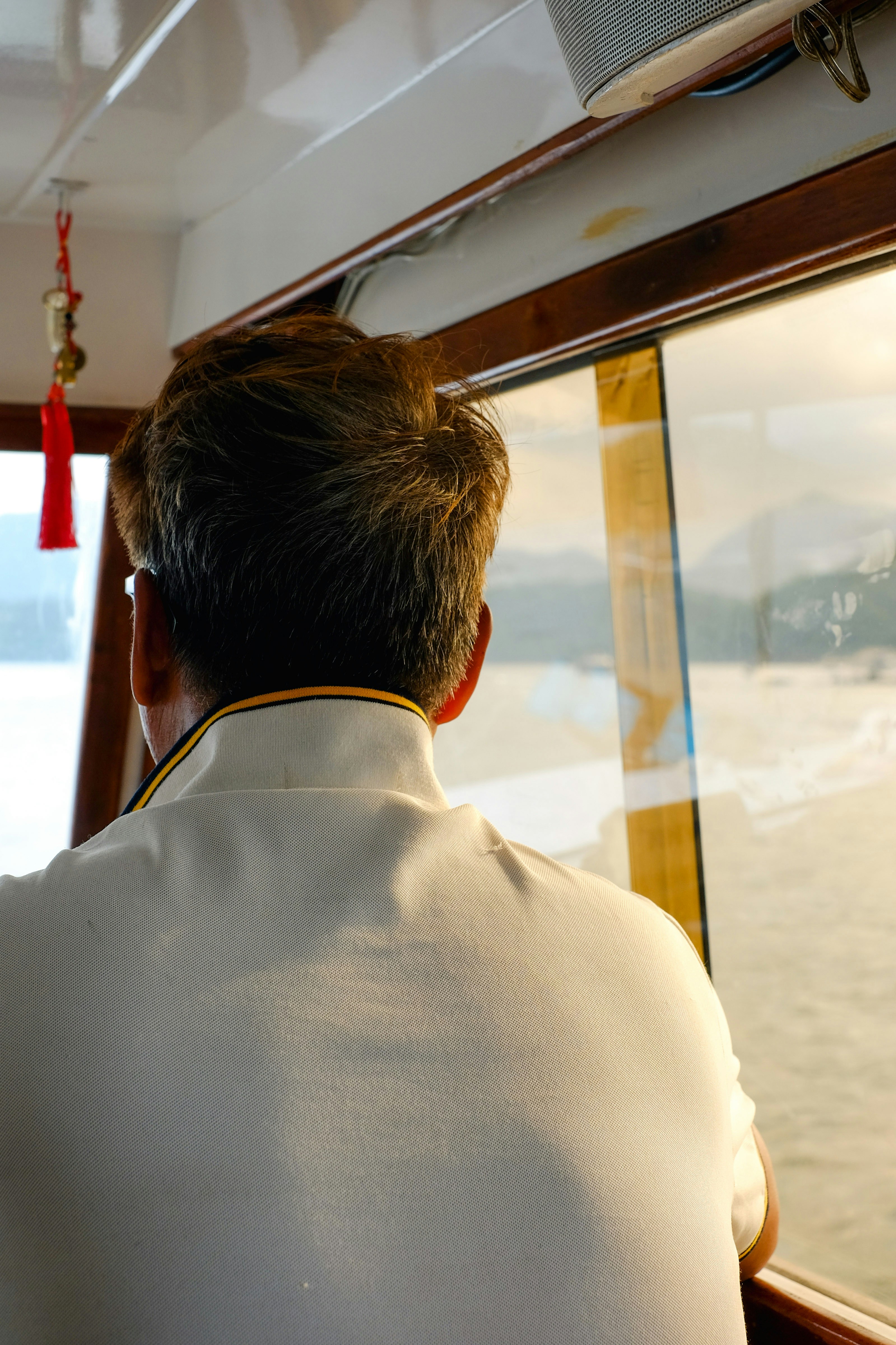A man is looking out the window of a boat