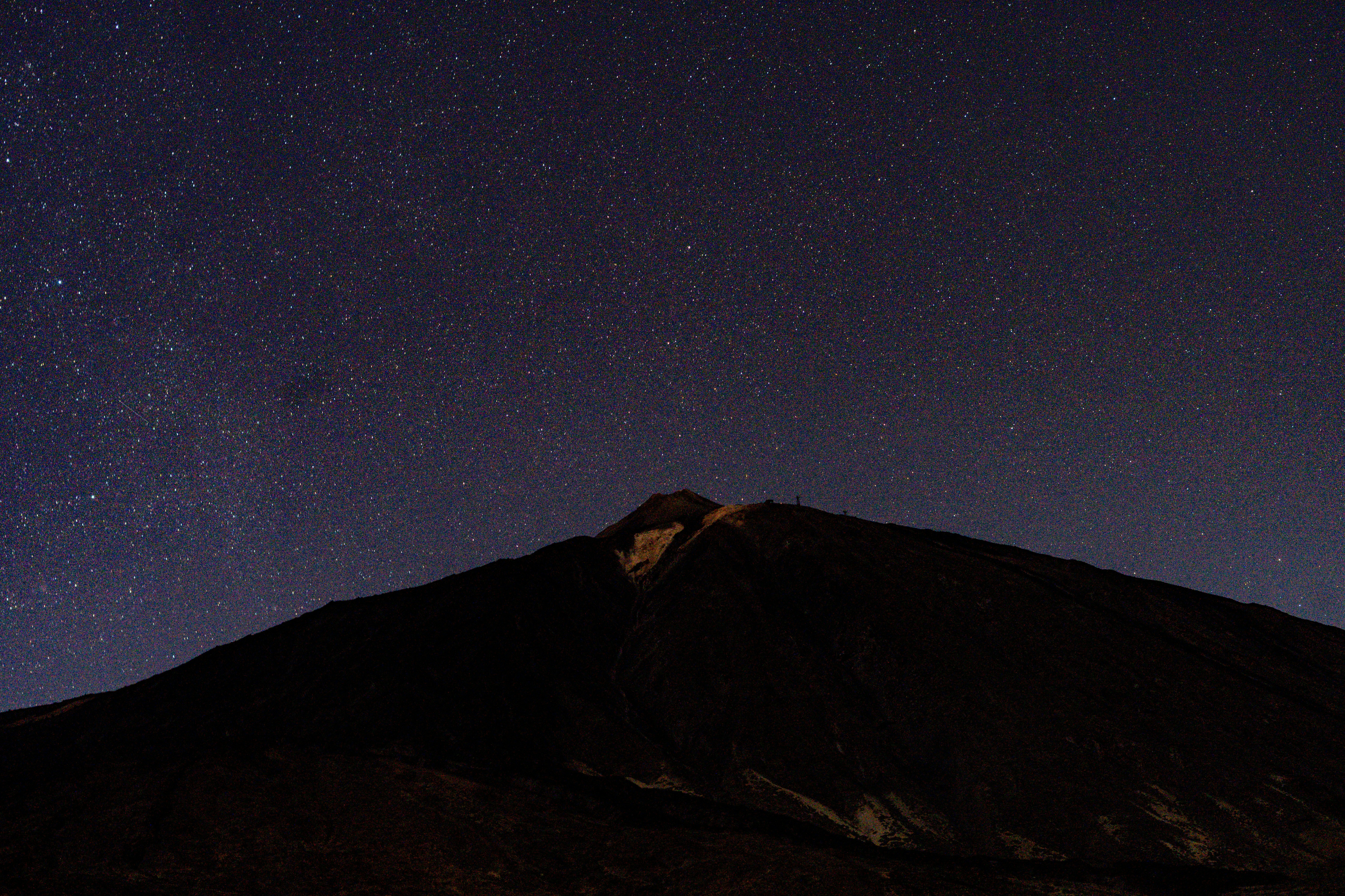 The night sky is full of stars above a mountain
