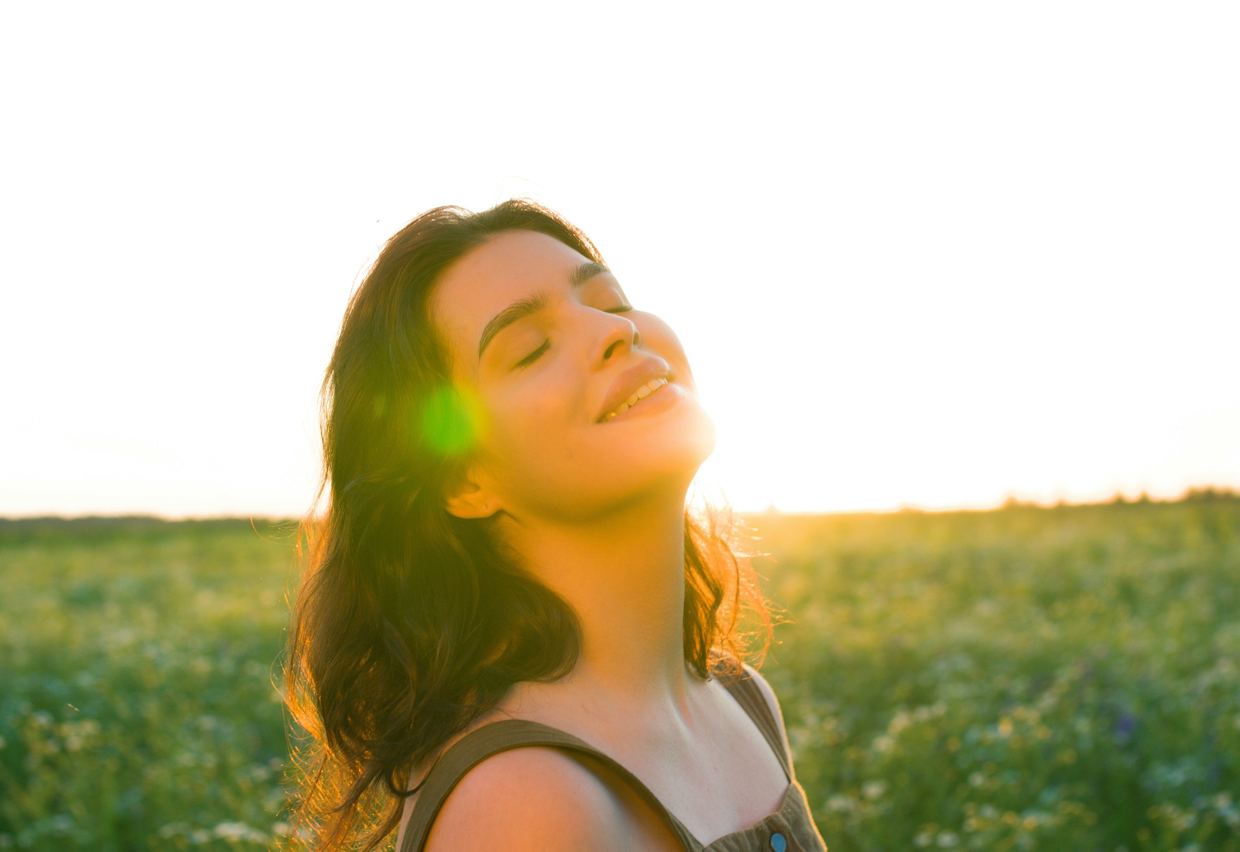 A woman standing in a field with her eyes closed