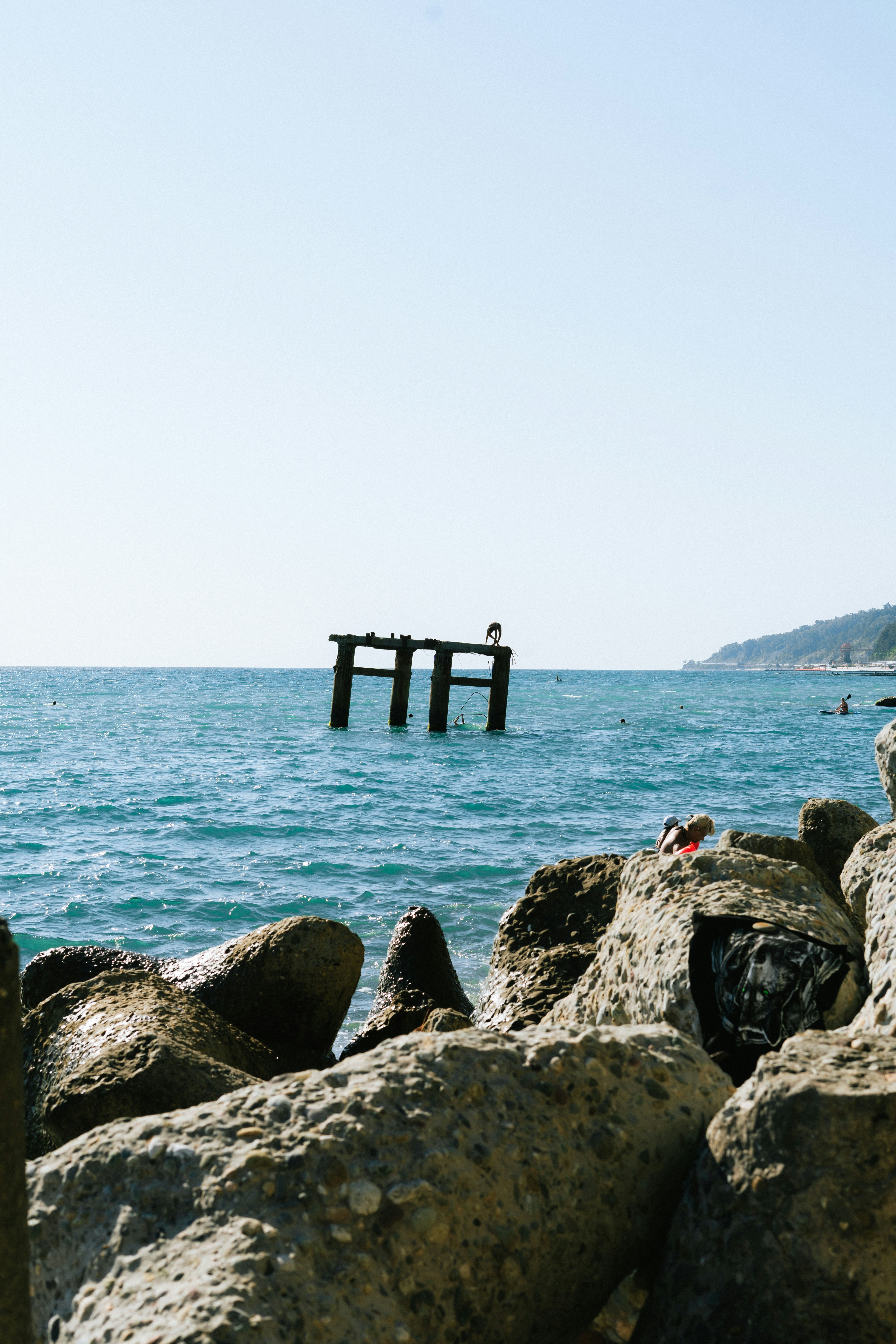 A person sitting on a rock near the ocean