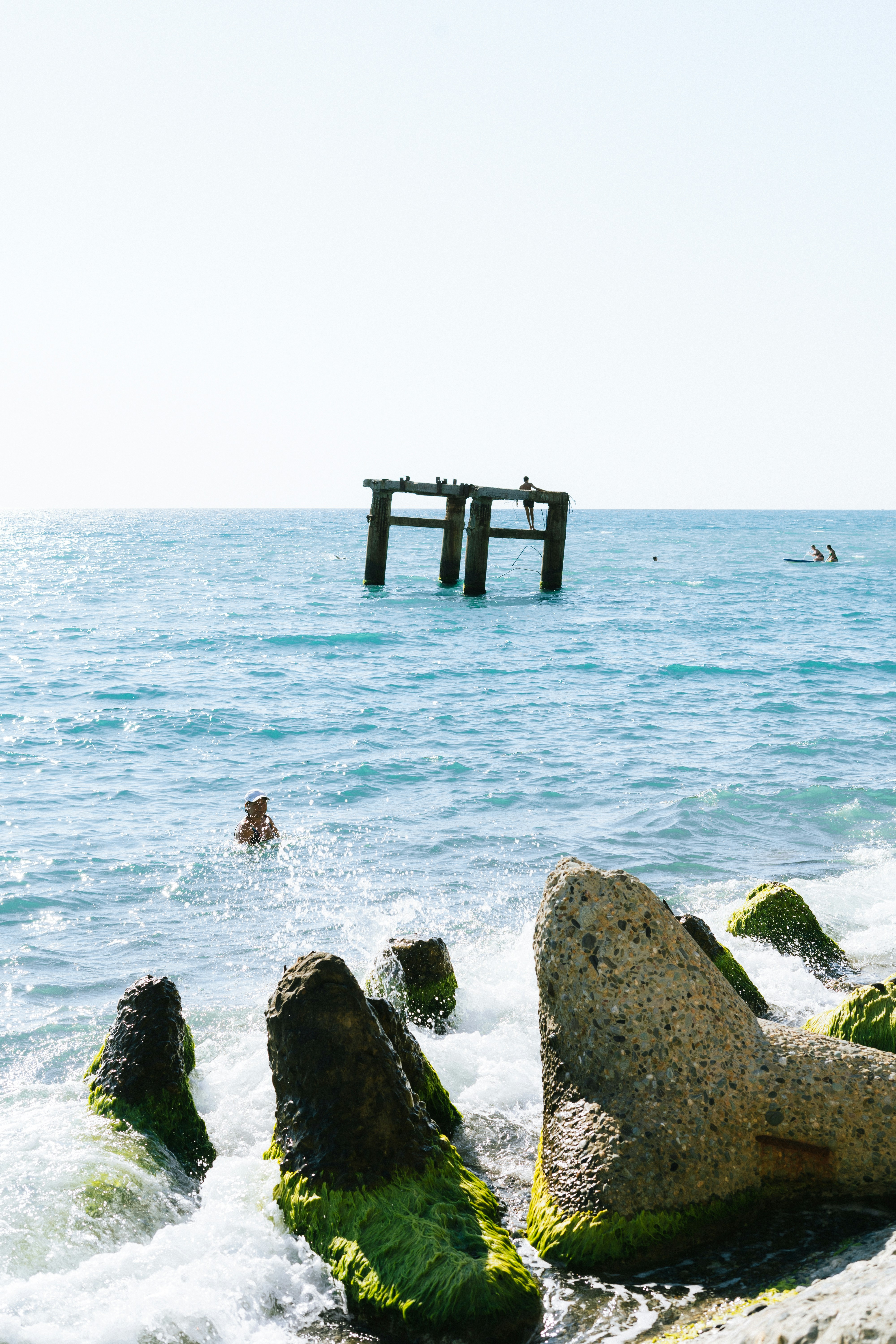 A person swimming in the ocean next to rocks