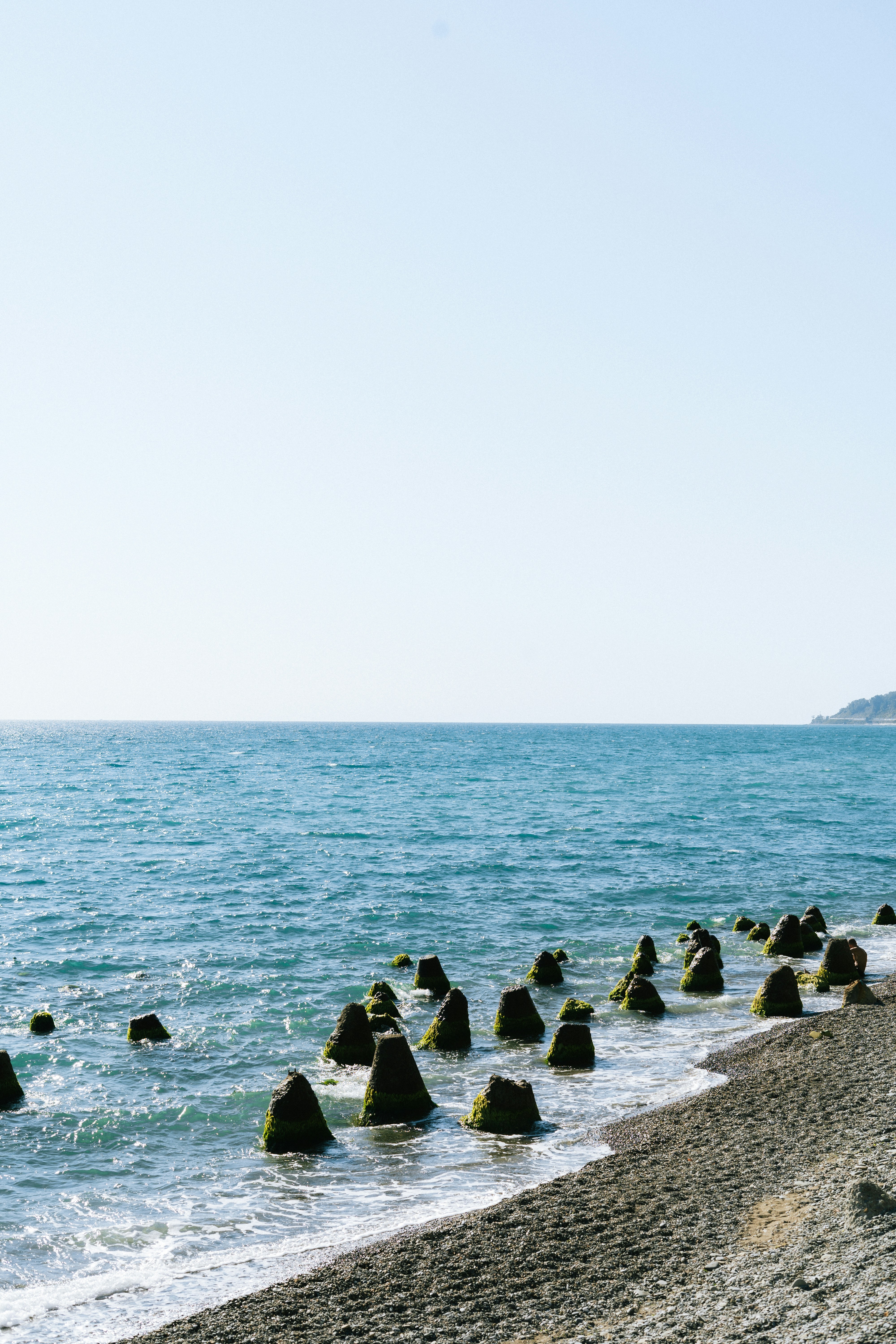 A group of rocks sitting on top of a beach next to the ocean