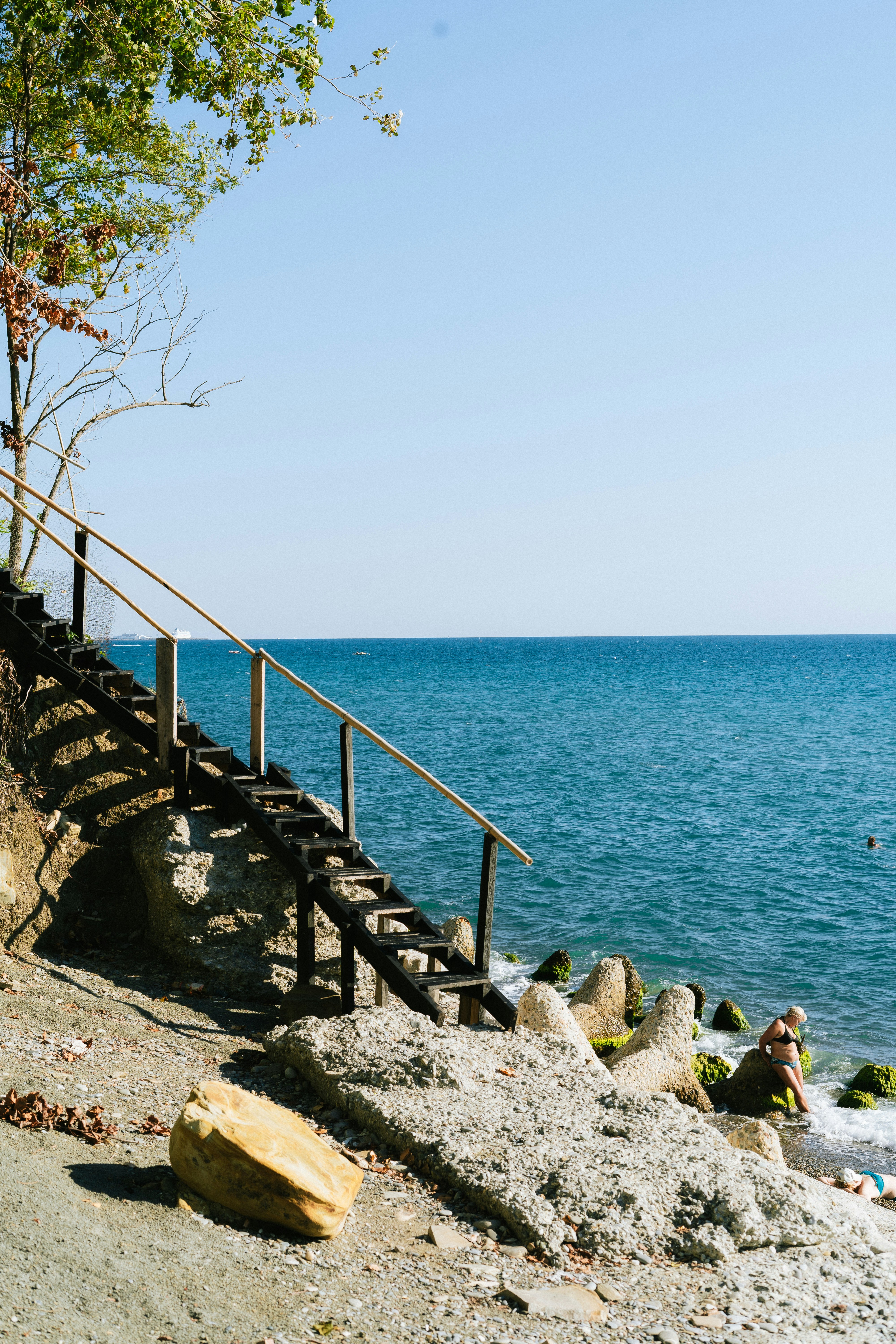 A person is sitting on a bench near the water