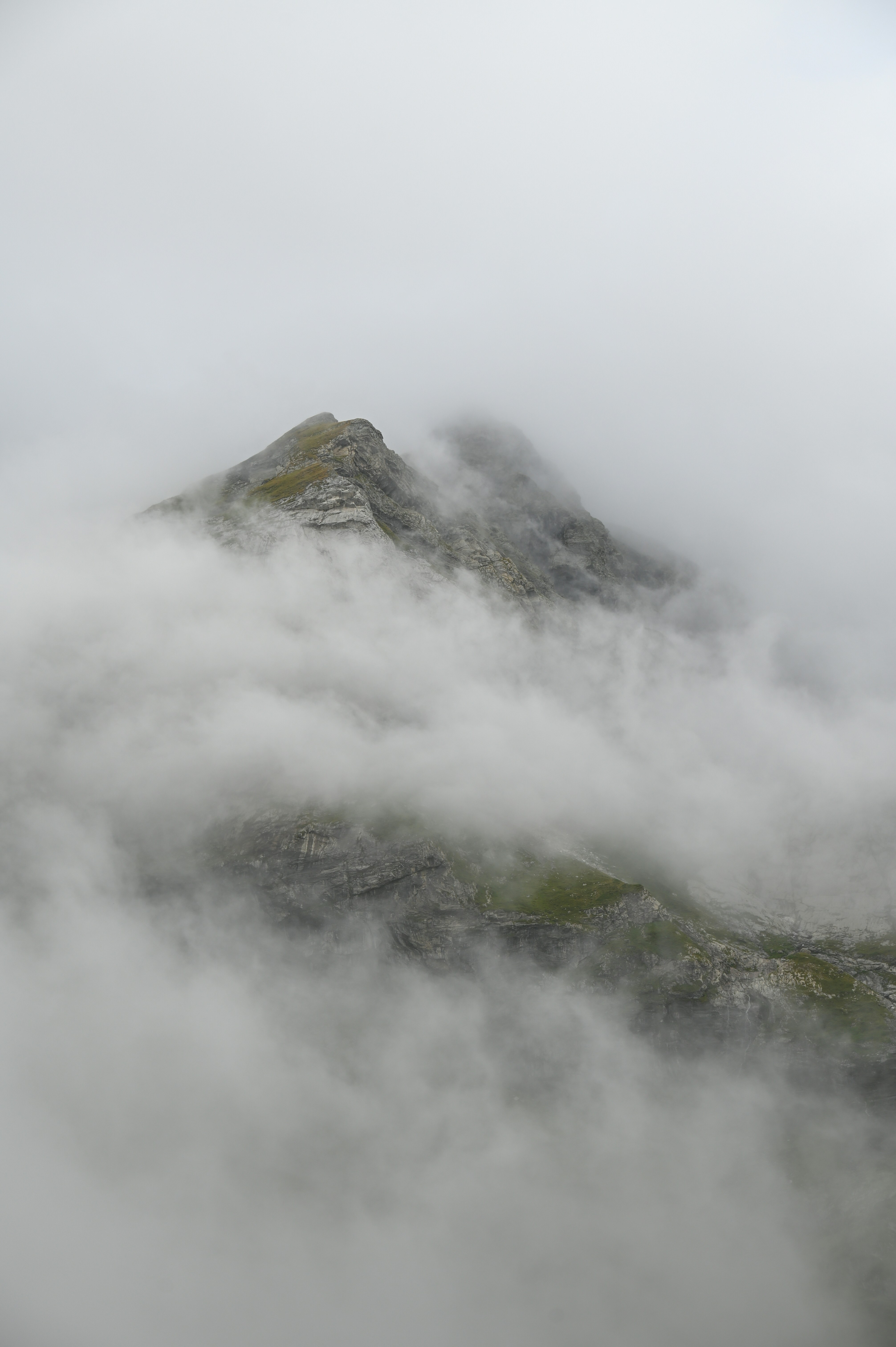 A mountain covered in fog and clouds on a cloudy day