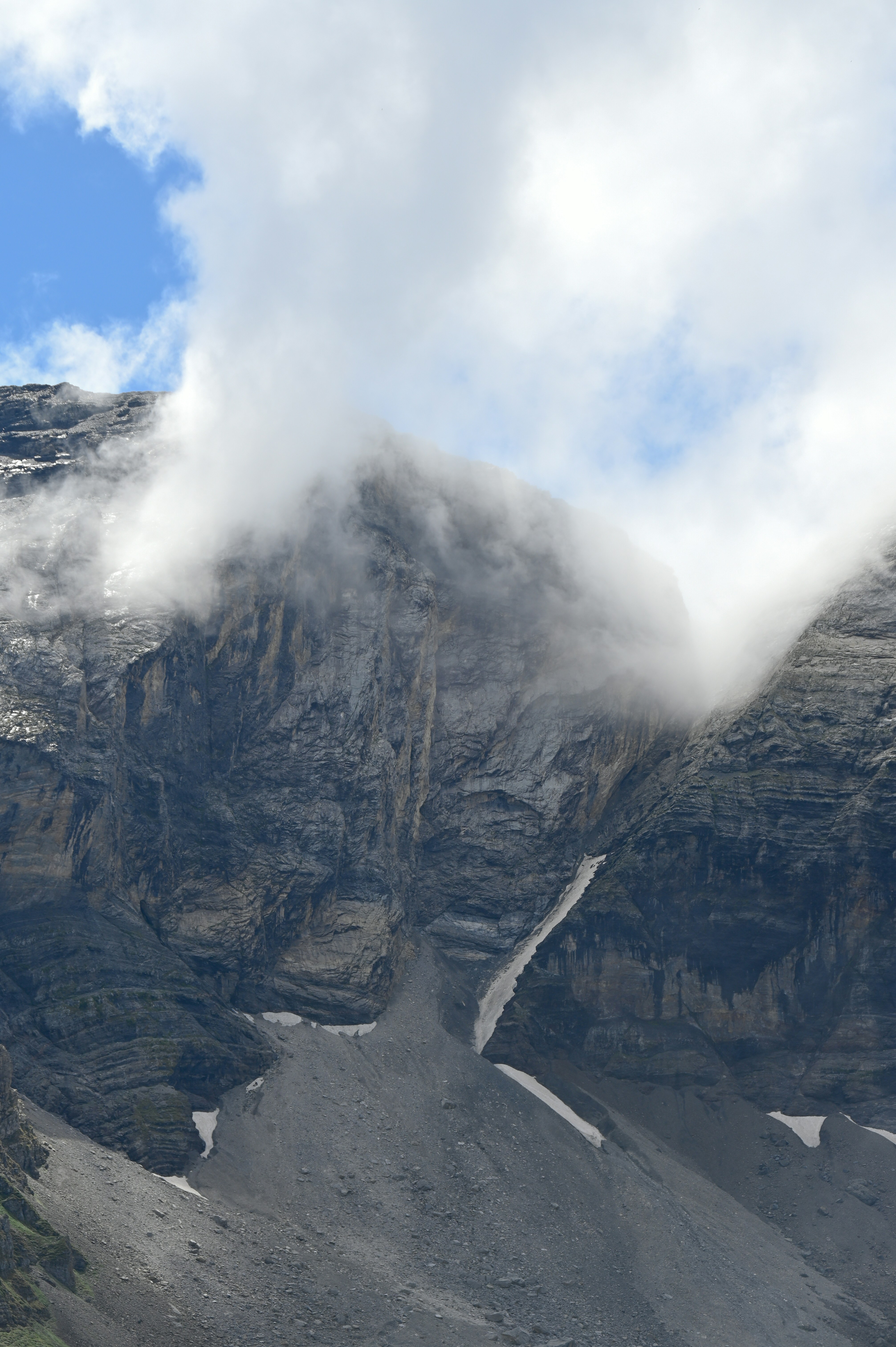 A very tall mountain with some clouds in the sky