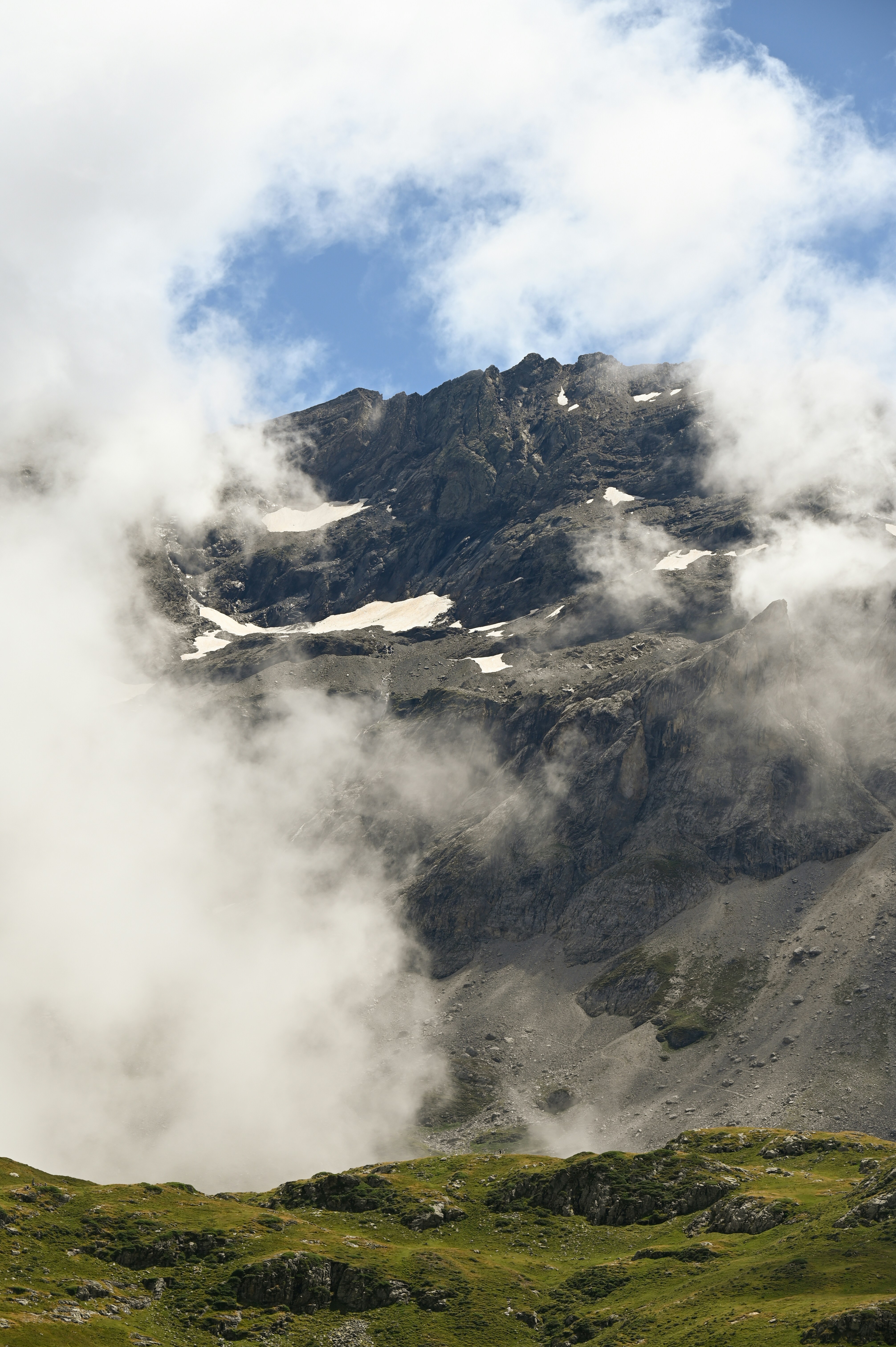 A mountain covered in fog and clouds on a sunny day
