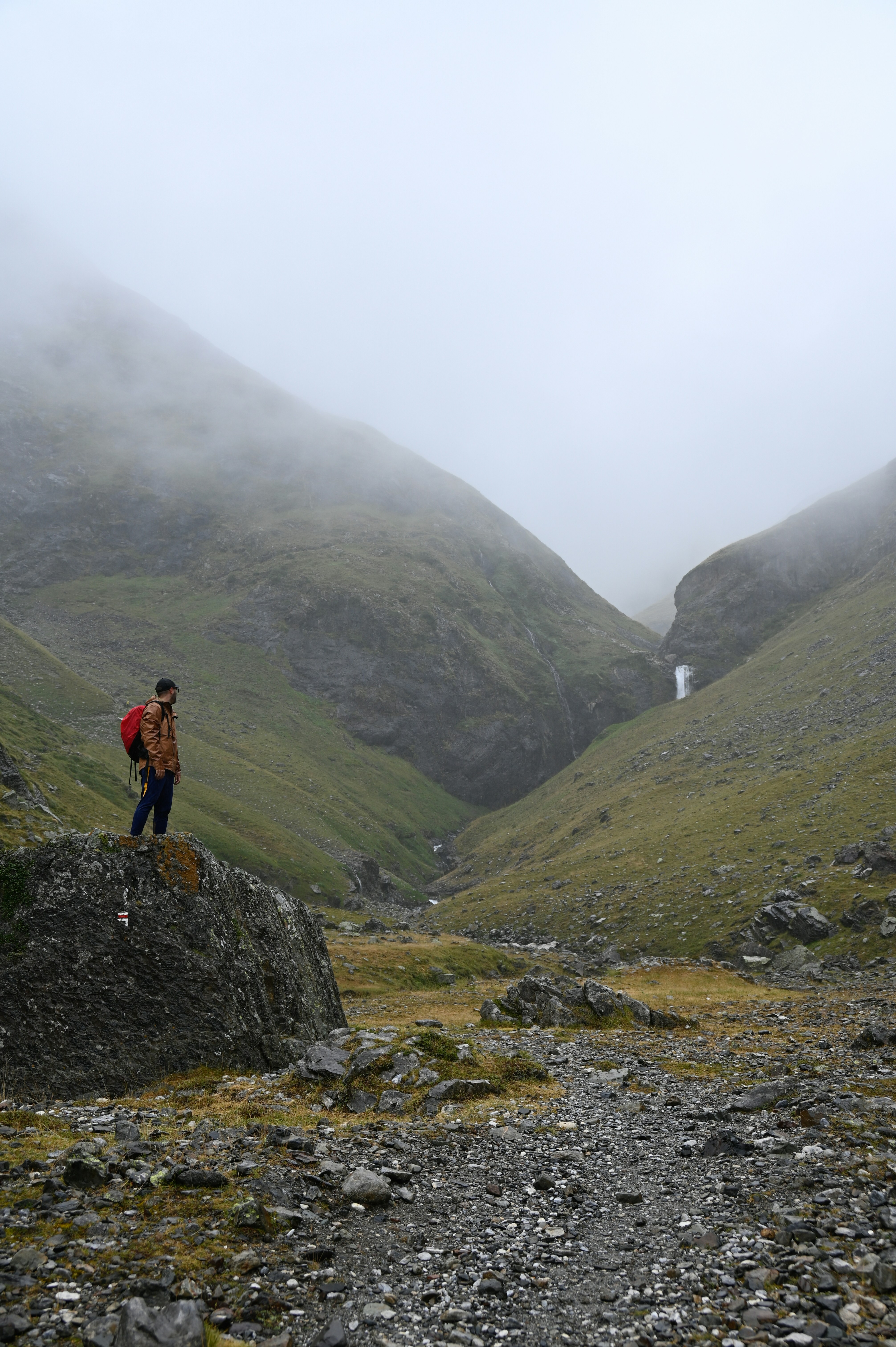 A man standing on a rock in the middle of a valley