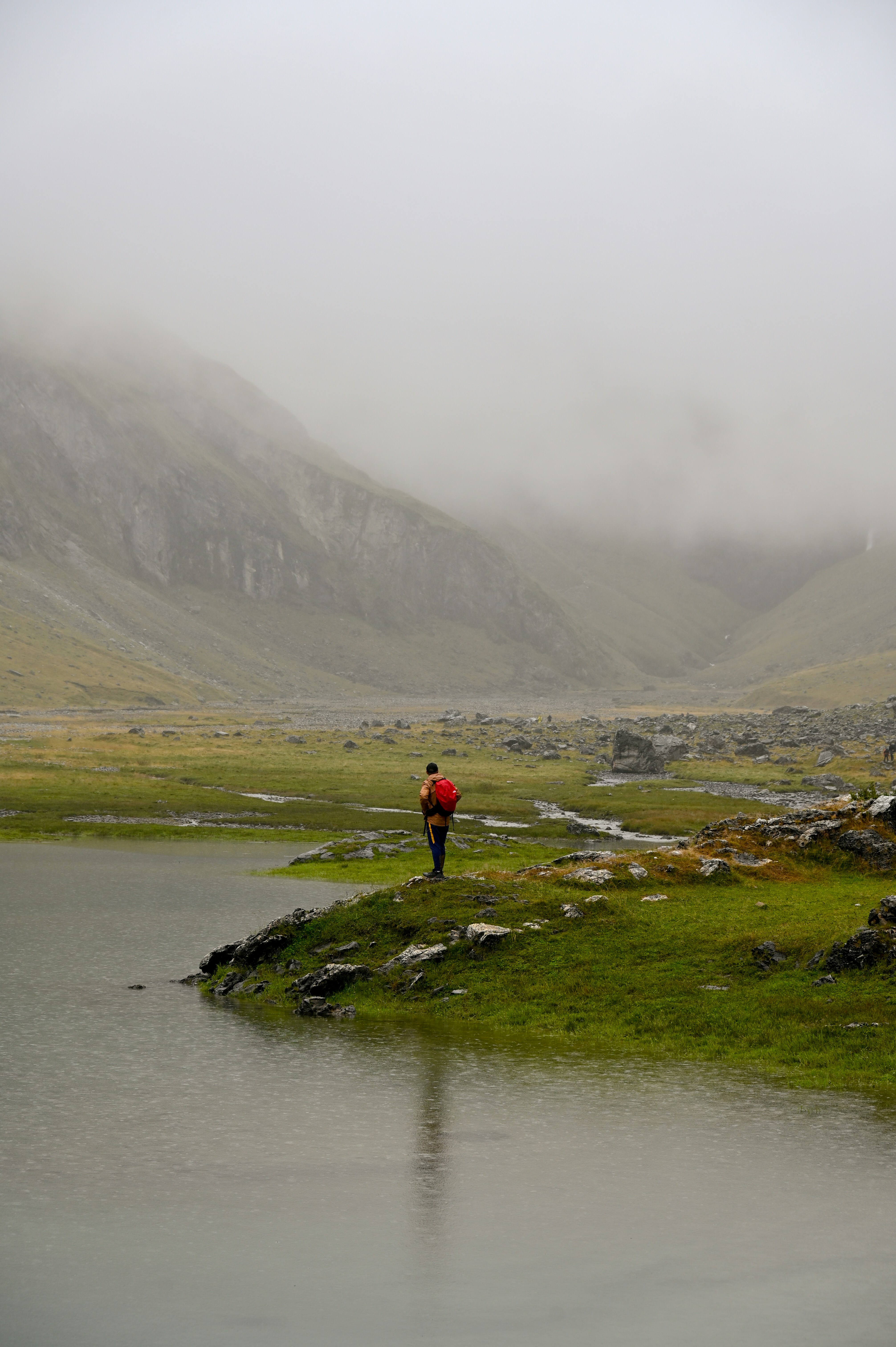 A person standing on a small island in the middle of a lake