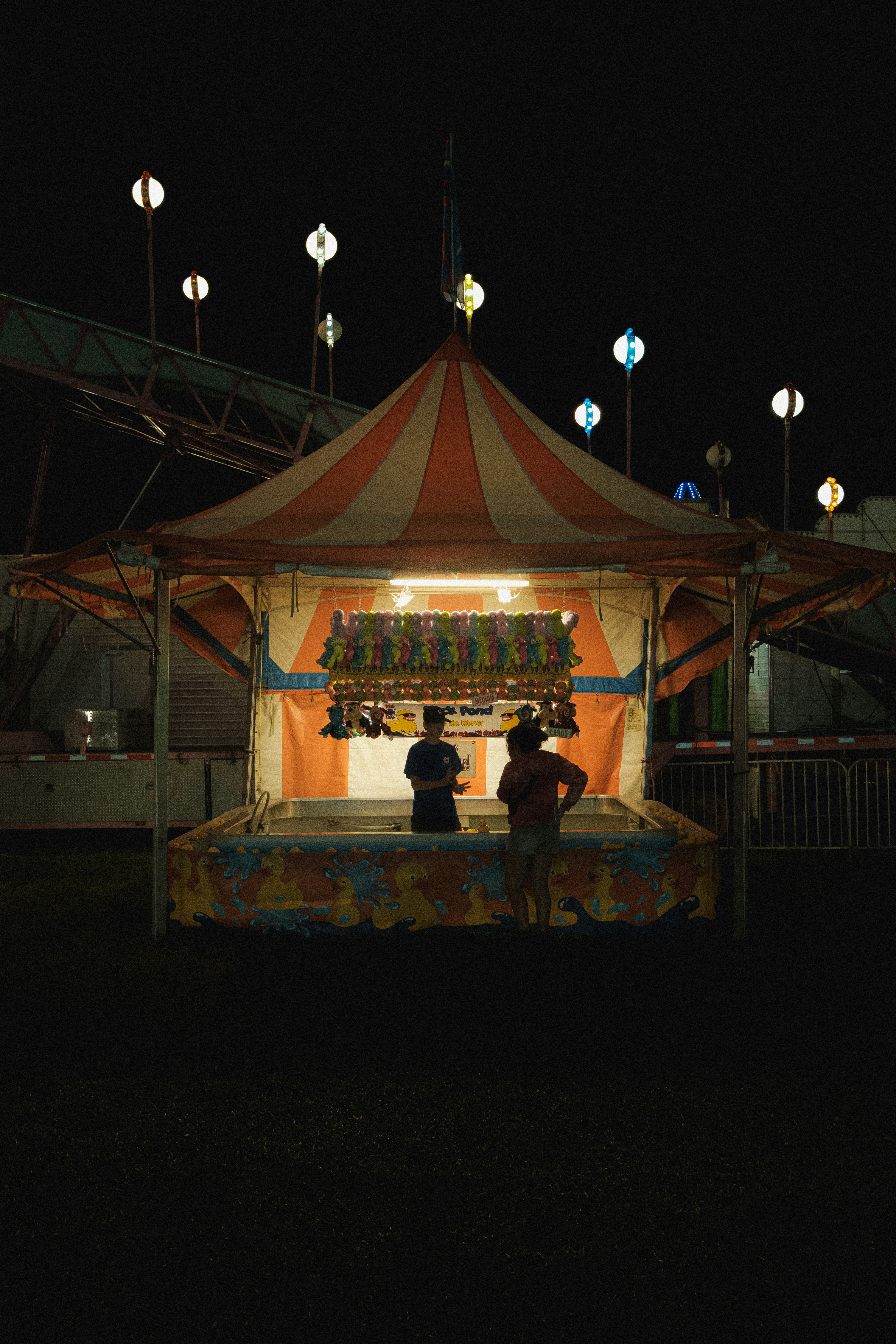 A circus tent at night with people standing in front of it