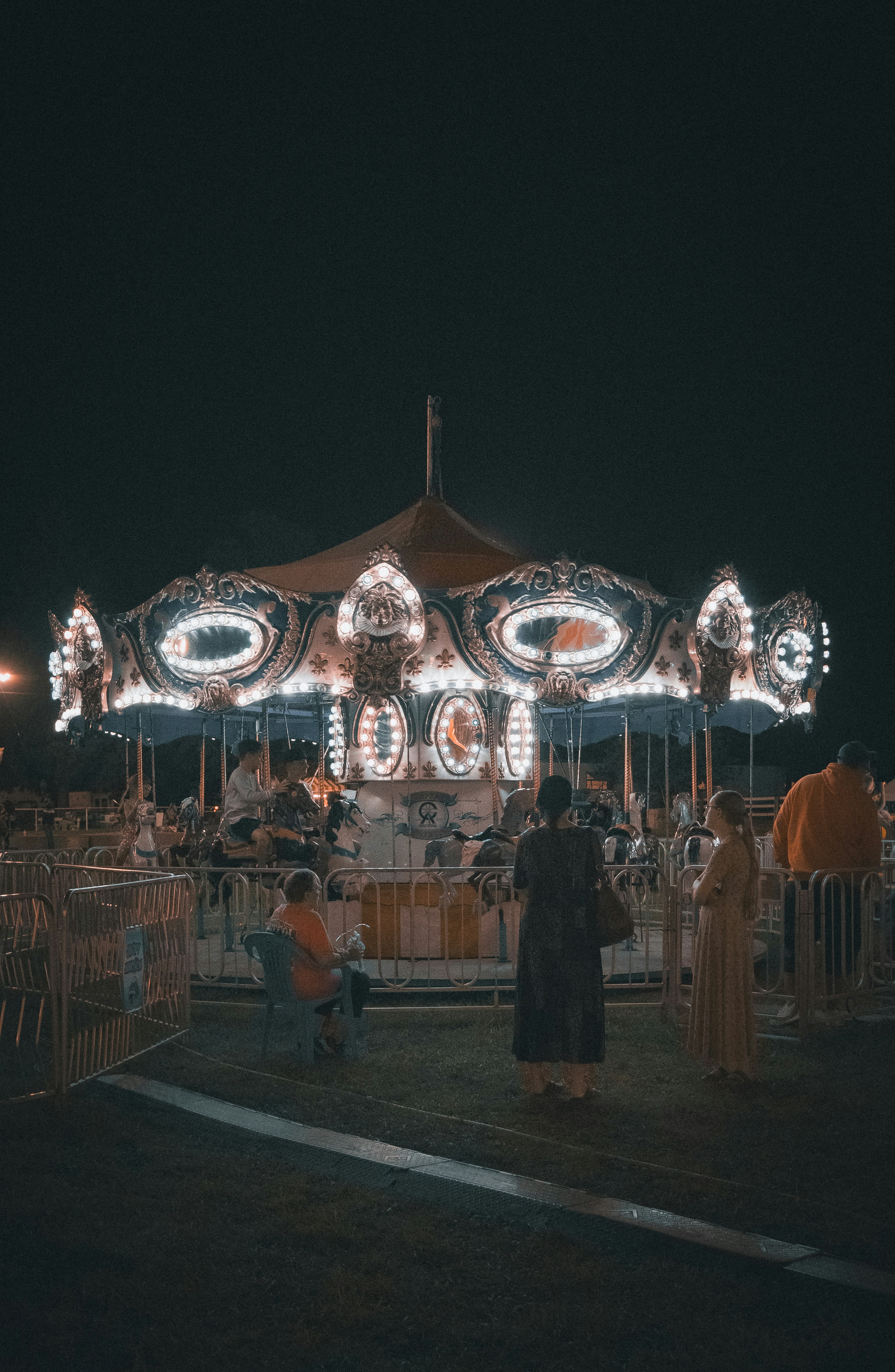 A merry go round at night with people standing around