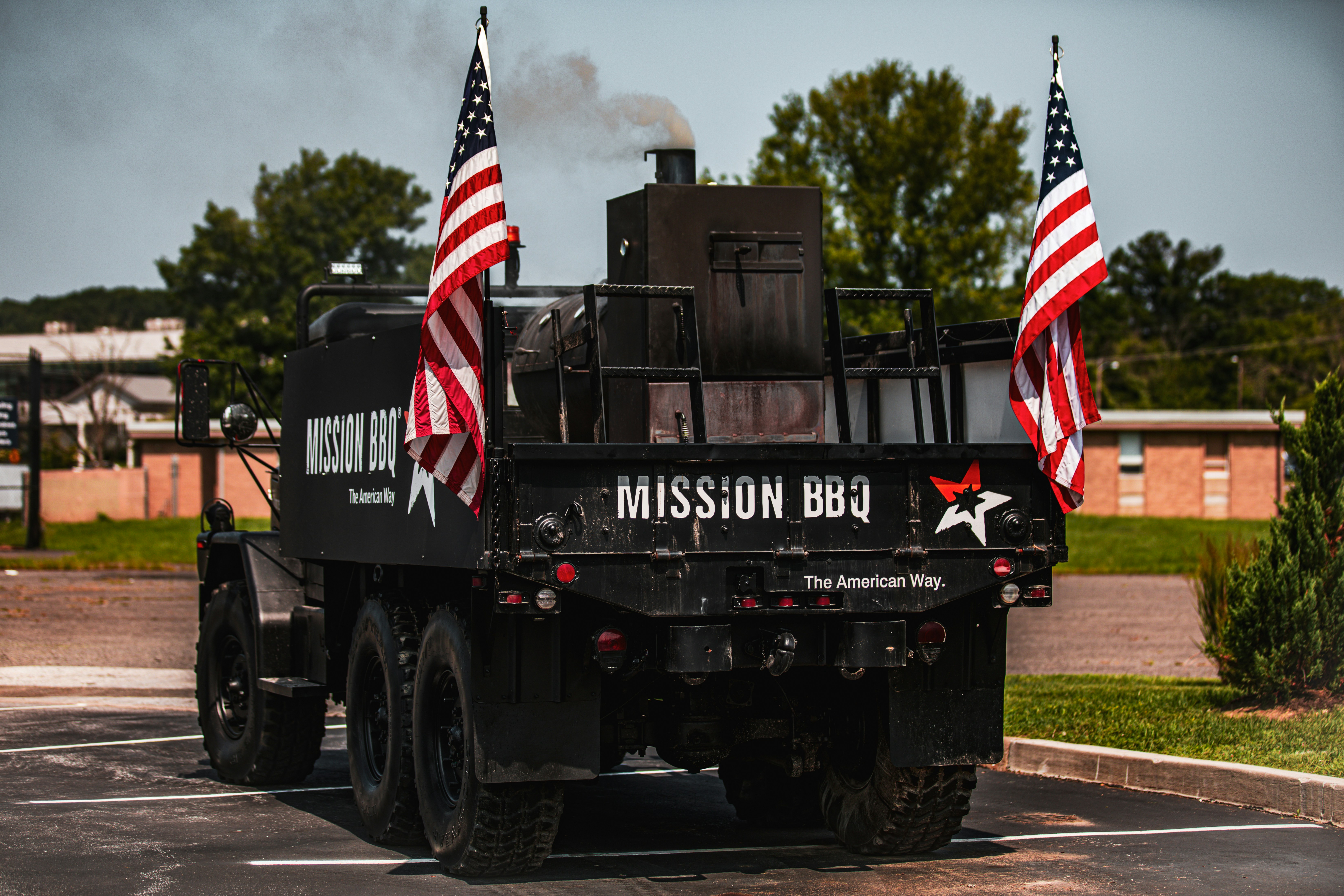 A military truck driving down a street with american flags