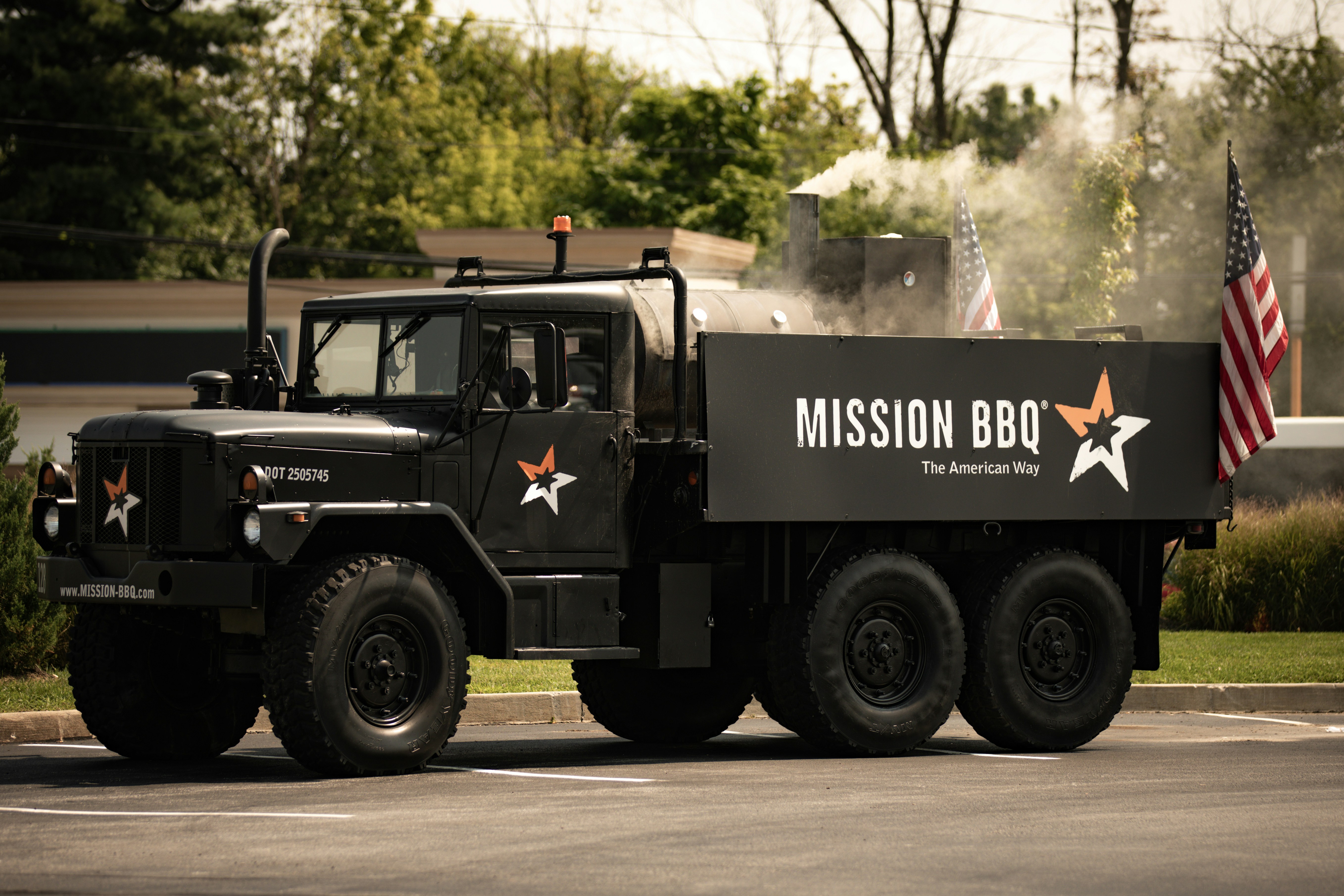 A military truck driving down a street next to an american flag