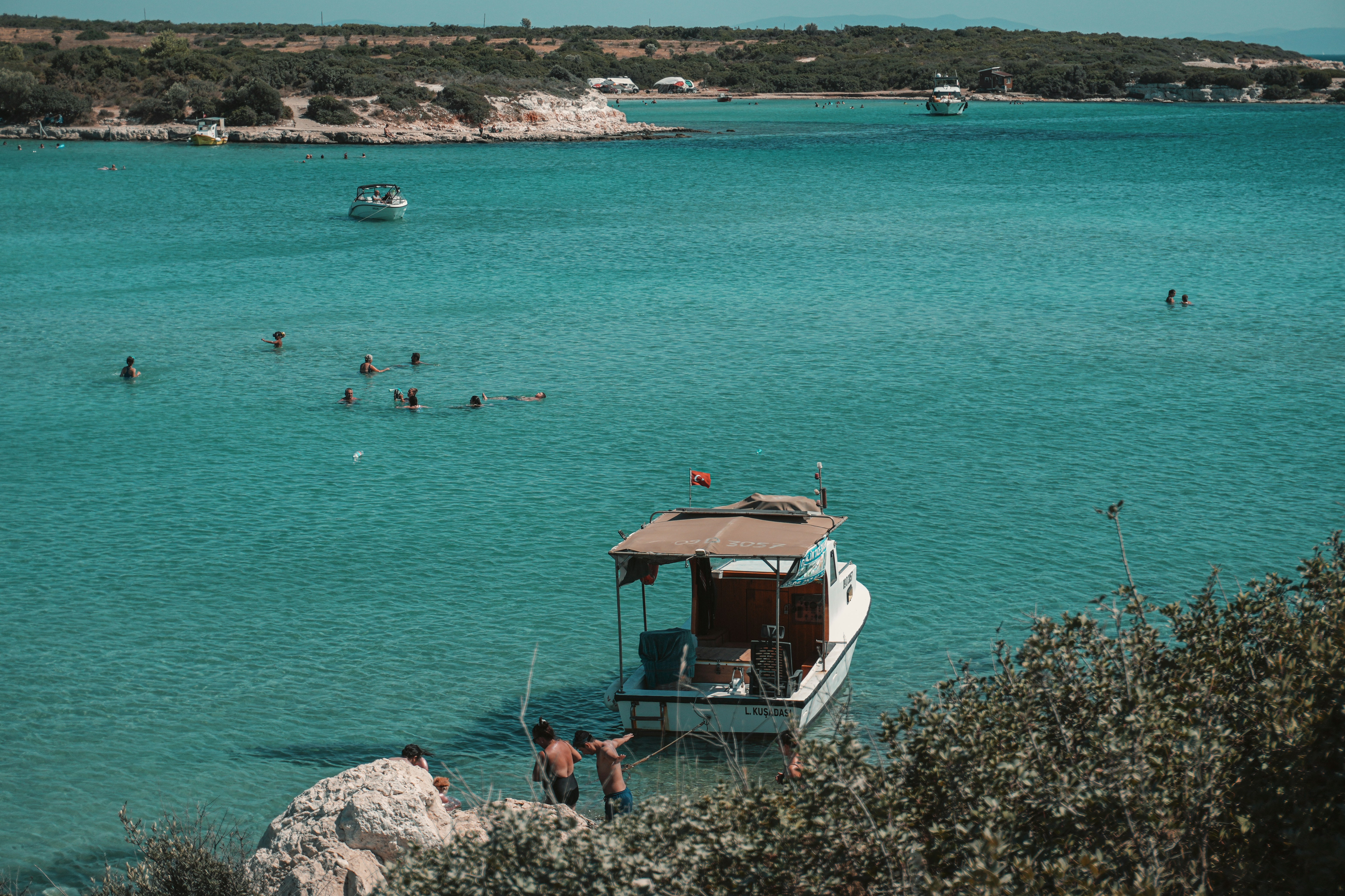 A boat in a body of water with people swimming in it