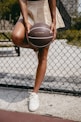 A woman holding a basketball in front of a fence