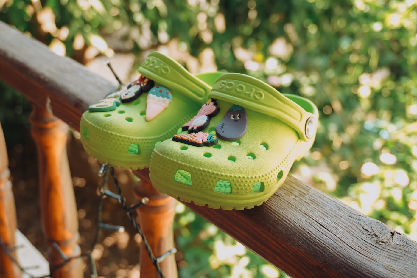 Bright green children sandals resting on a wooden playground rail