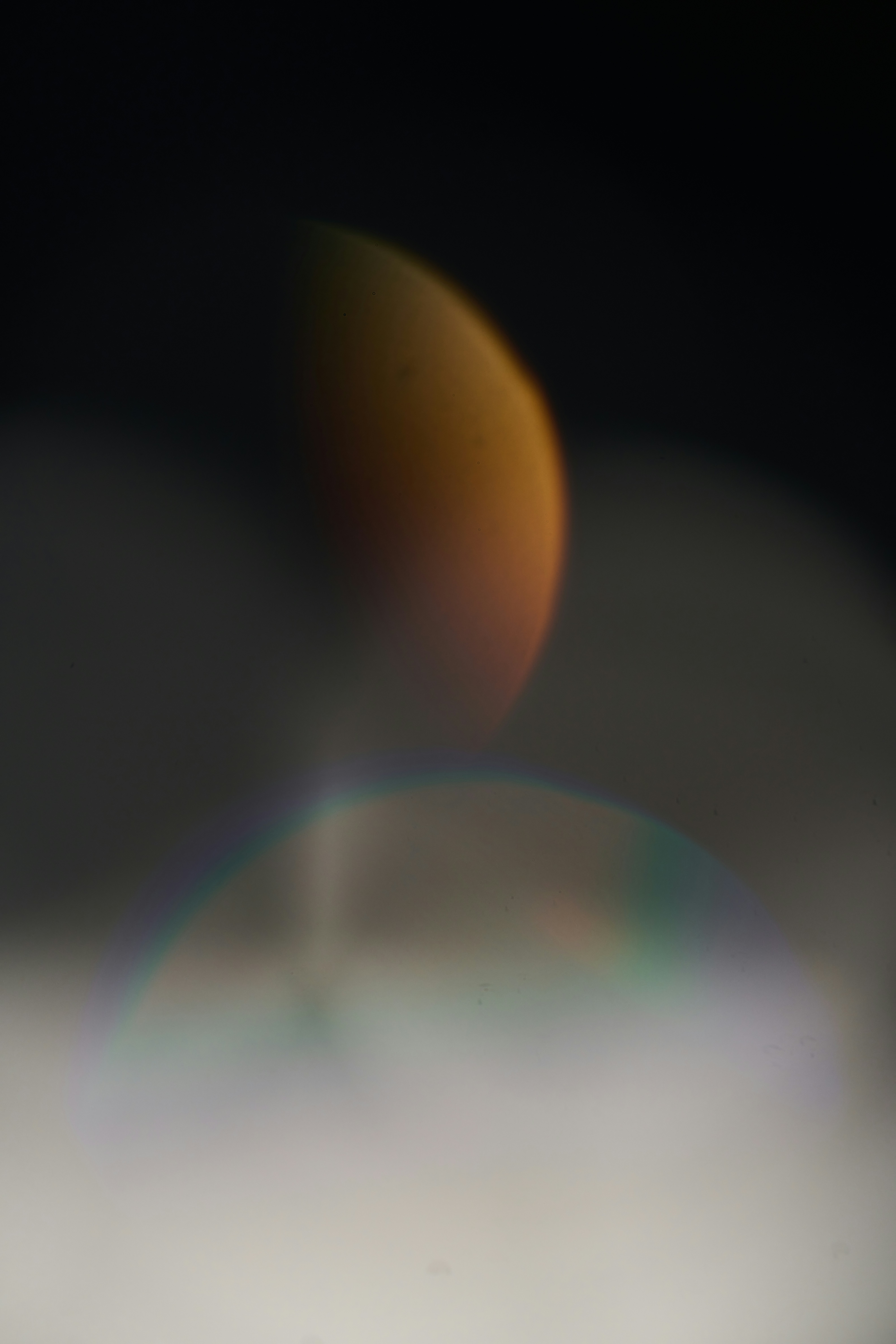 A blurry photo of a half moon and the sun