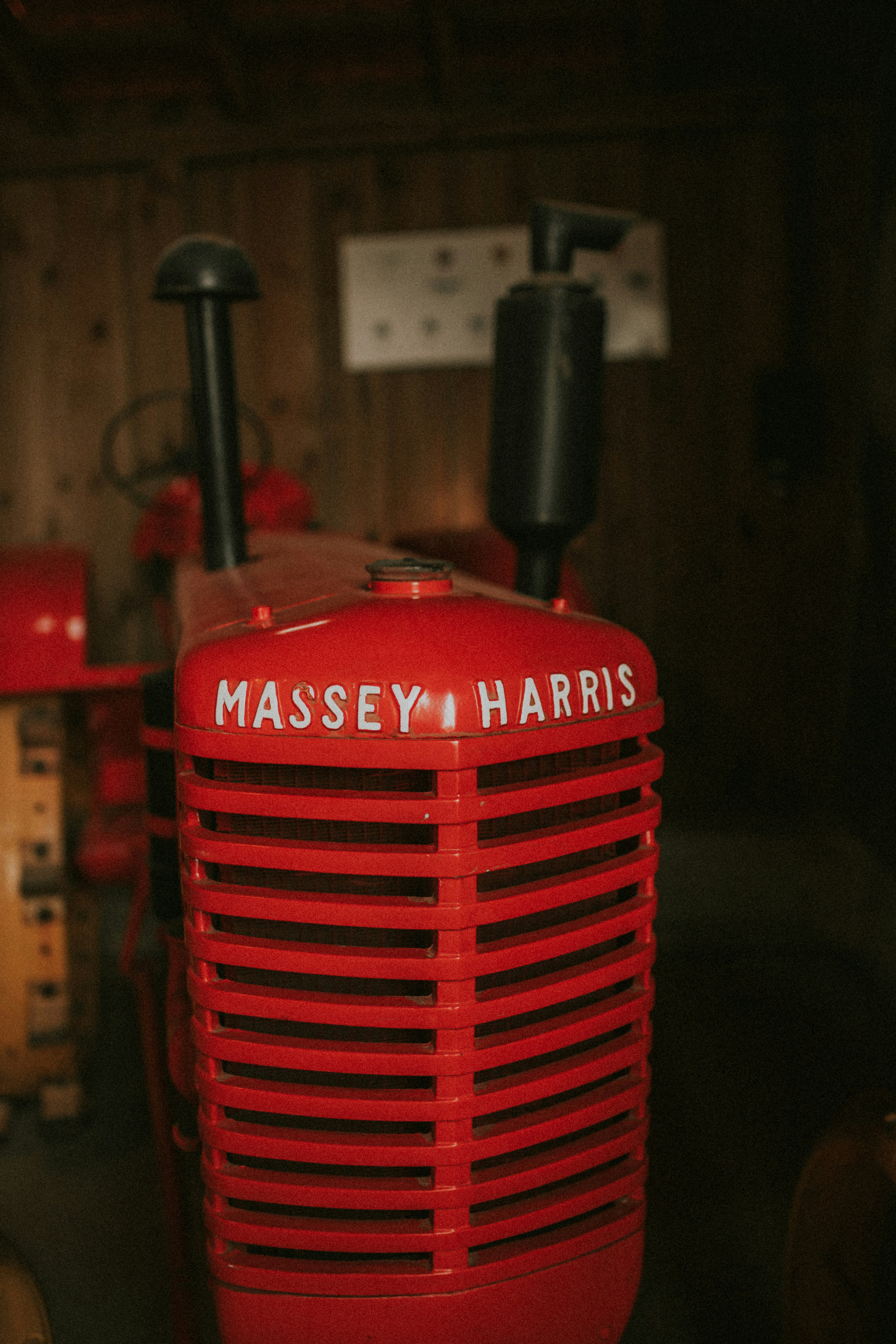 A red tractor sitting in a garage next to a wooden wall
