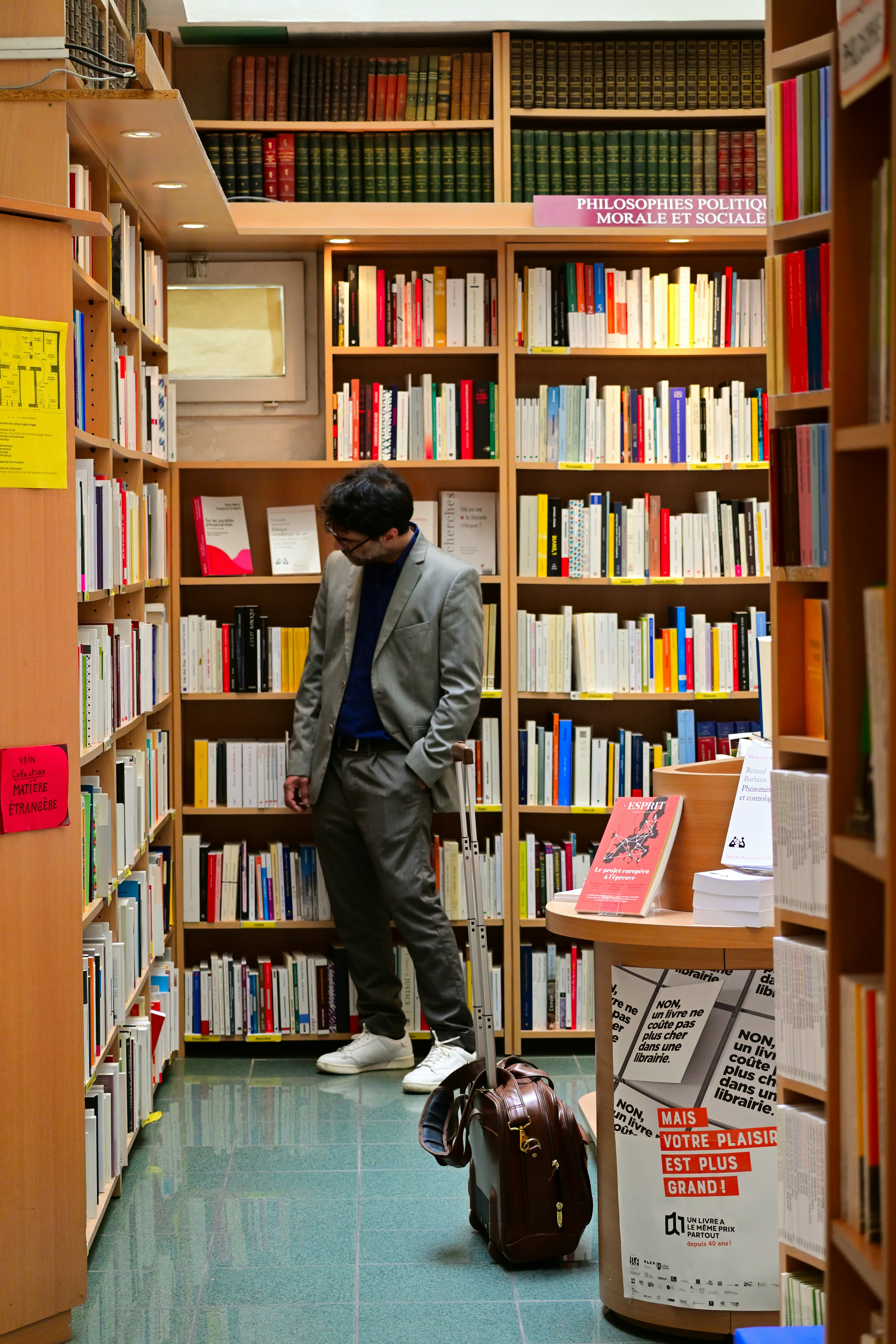 A man standing in a library with a suitcase