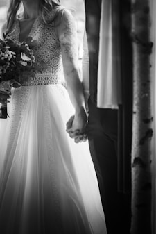 A bride and groom holding hands in front of a window