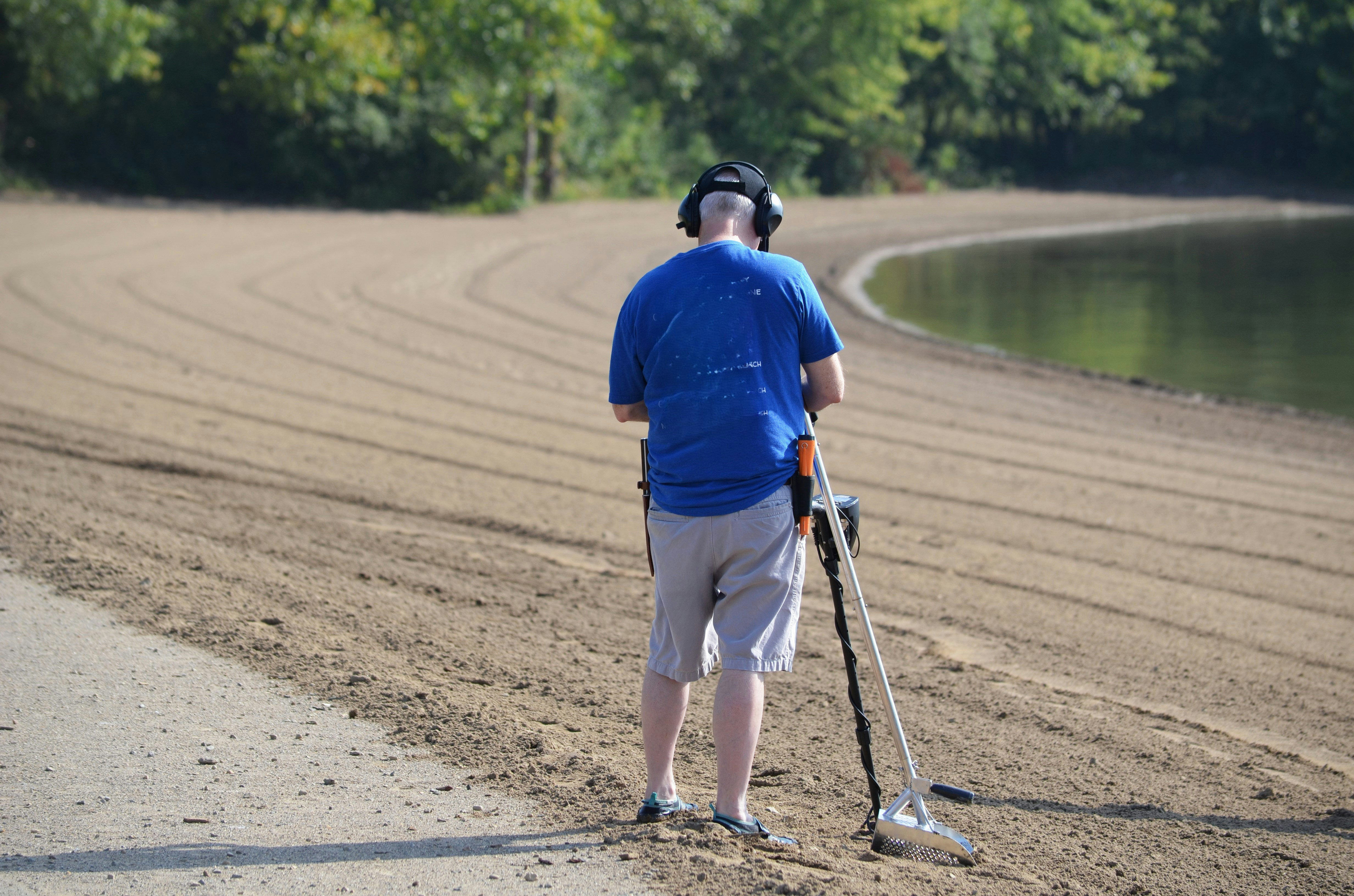 A man standing on a dirt road holding a walking stick