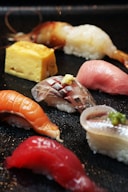 A variety of sushi on a black plate