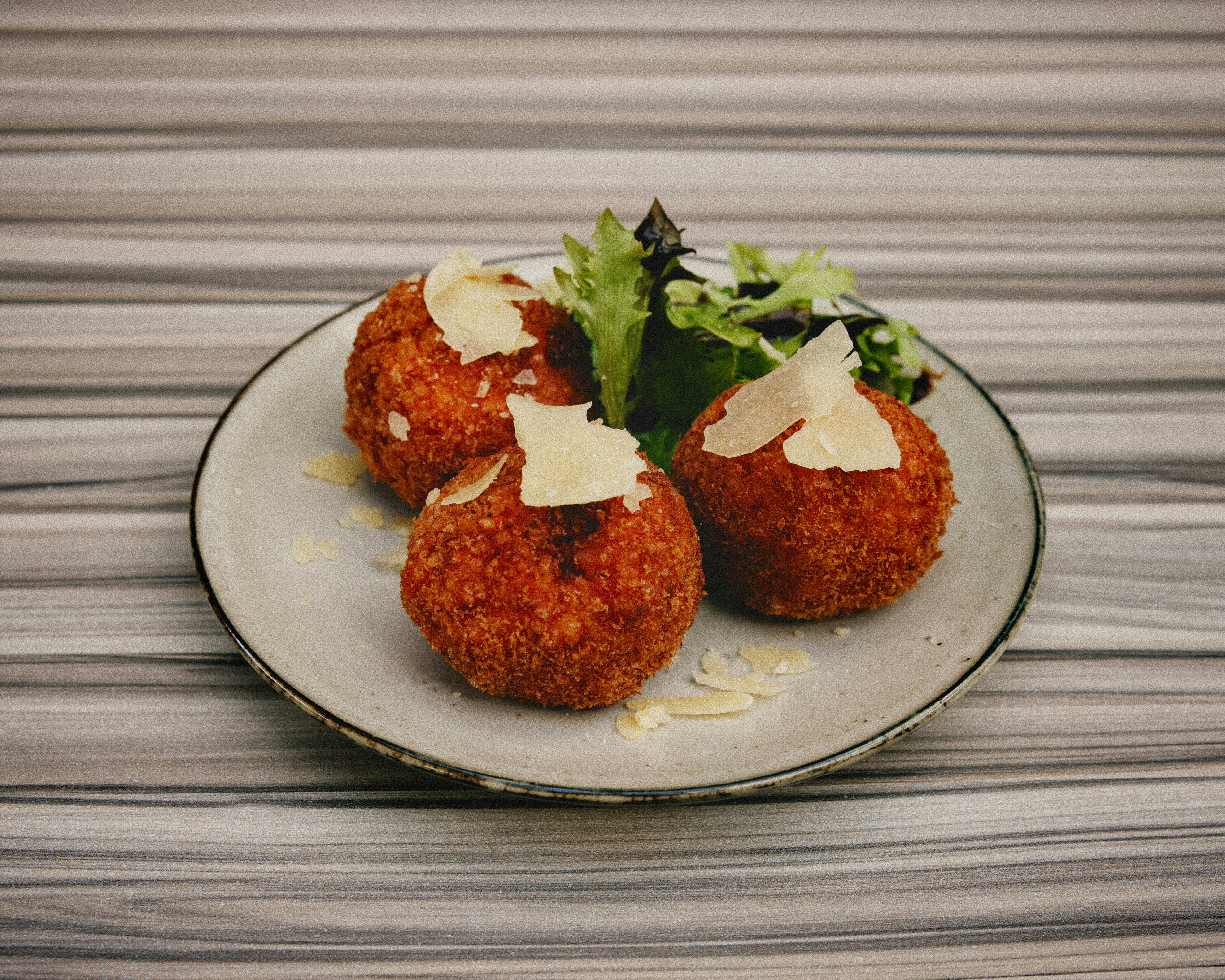 A white plate topped with meatballs covered in cheese