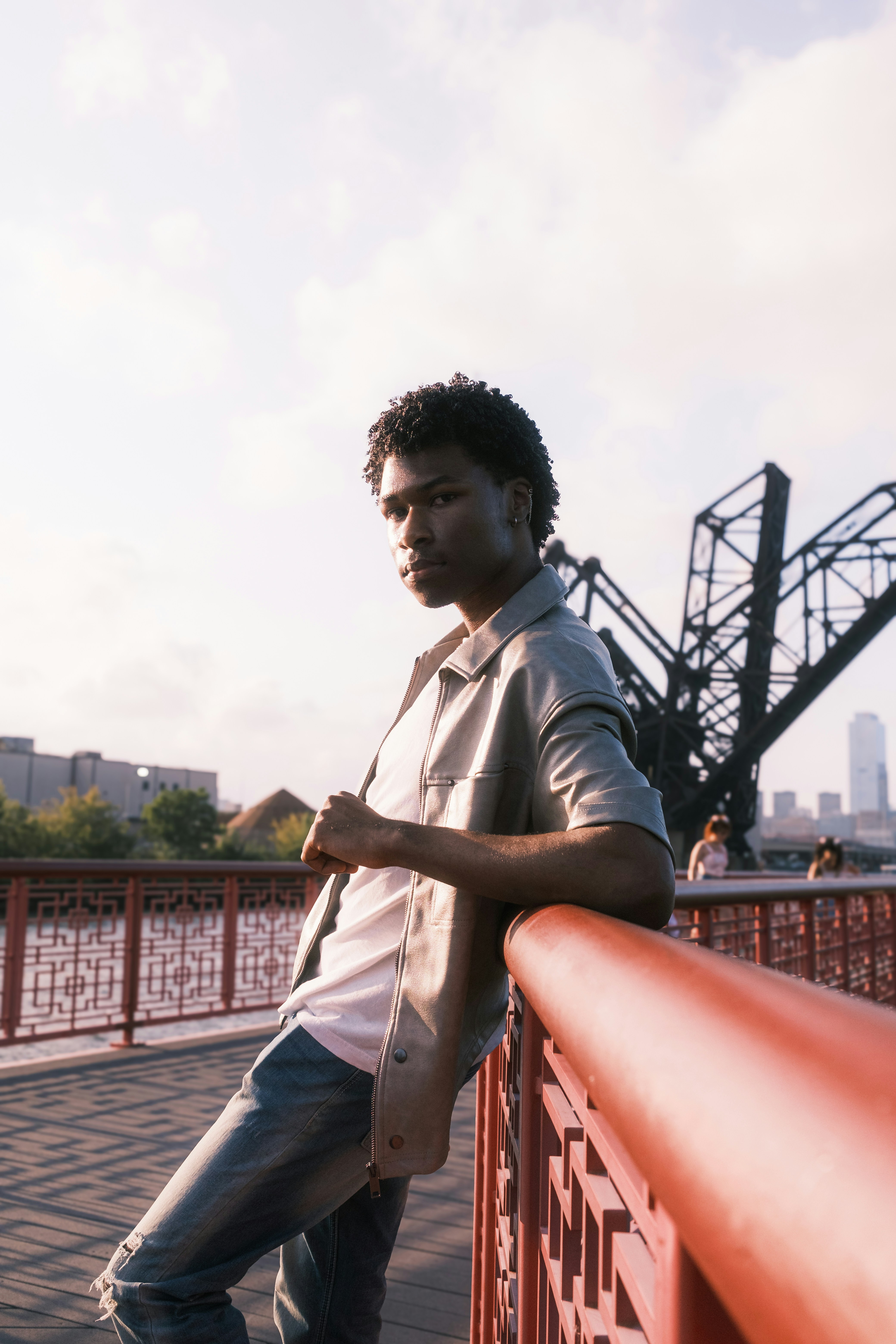 Um homem apoiado em um trilho perto de uma ponte