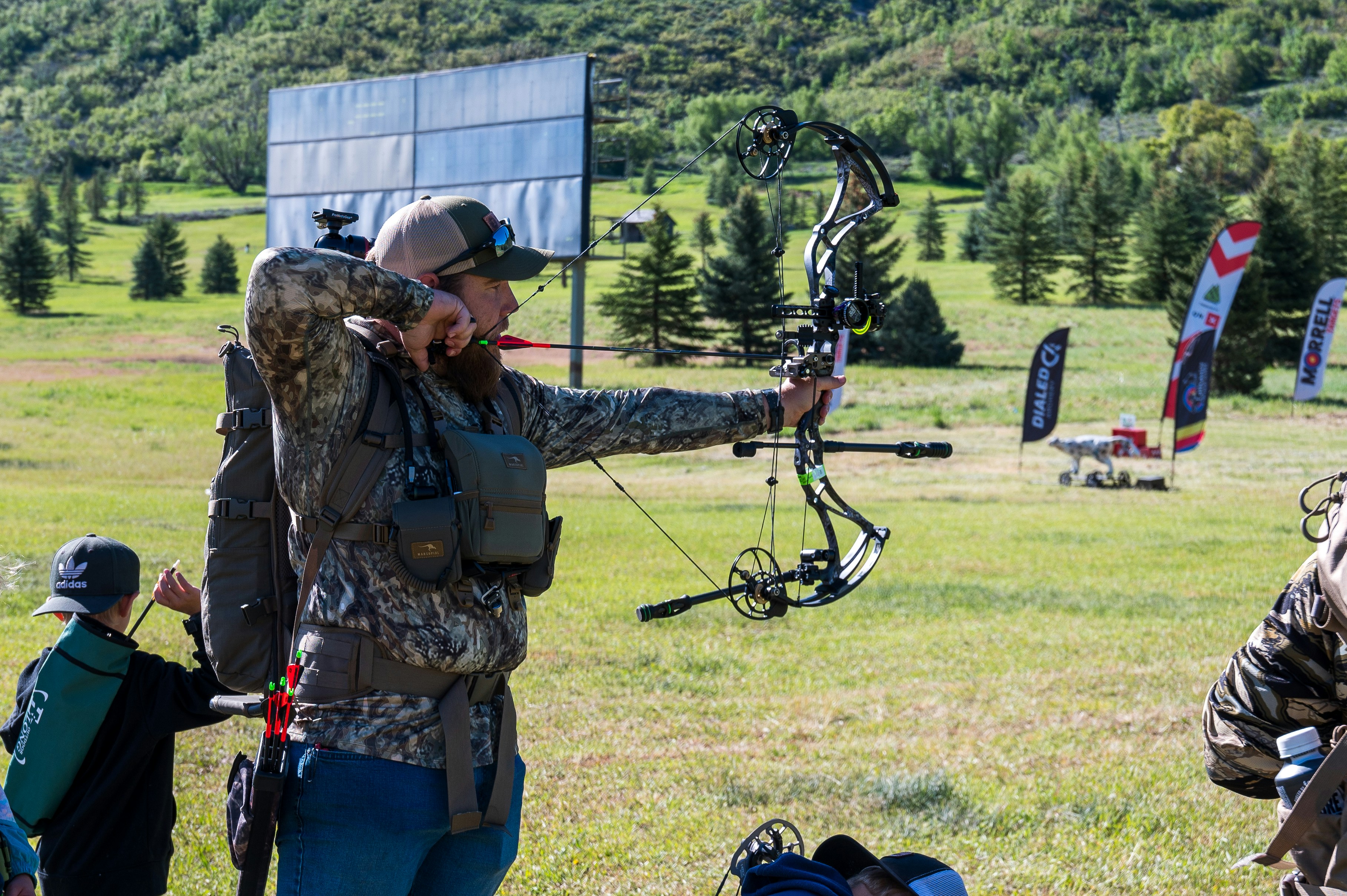 A man holding a bow while standing in a field