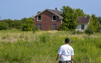 A man standing in a field next to a house
