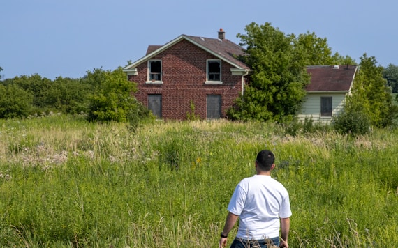 A man standing in a field next to a house