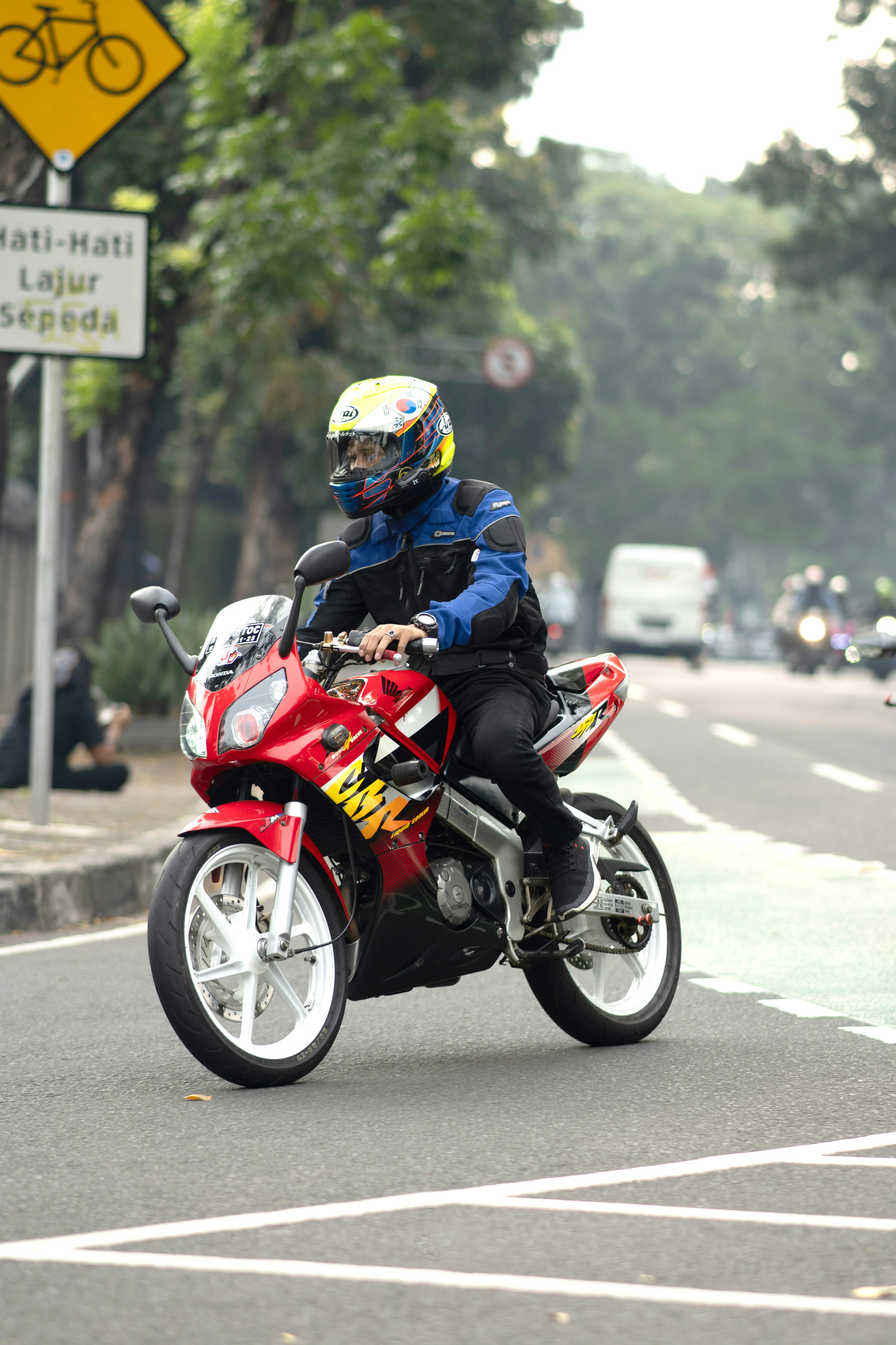 A man riding a red motorcycle down a street